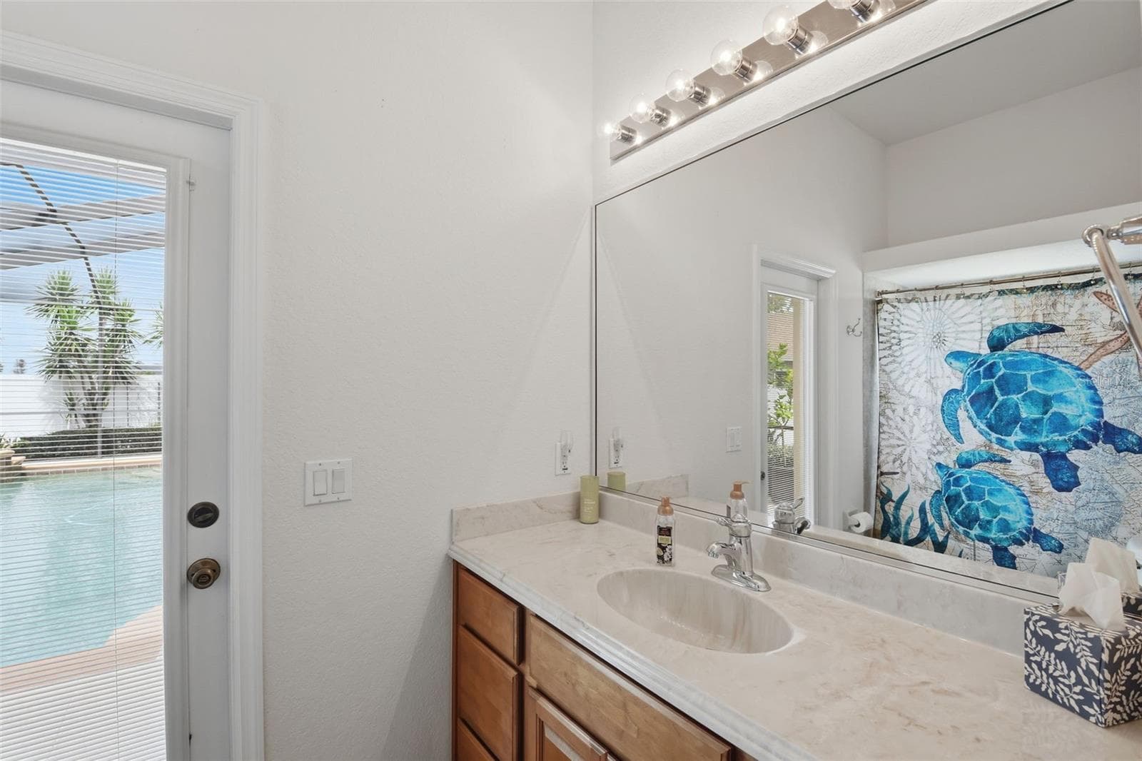 Pool Bathroom – Convenient pool-access bath featuring a wood vanity, generous mirror, and direct exterior access just steps from the pool area. - 114 VIOLA DR, AUBURNDALE