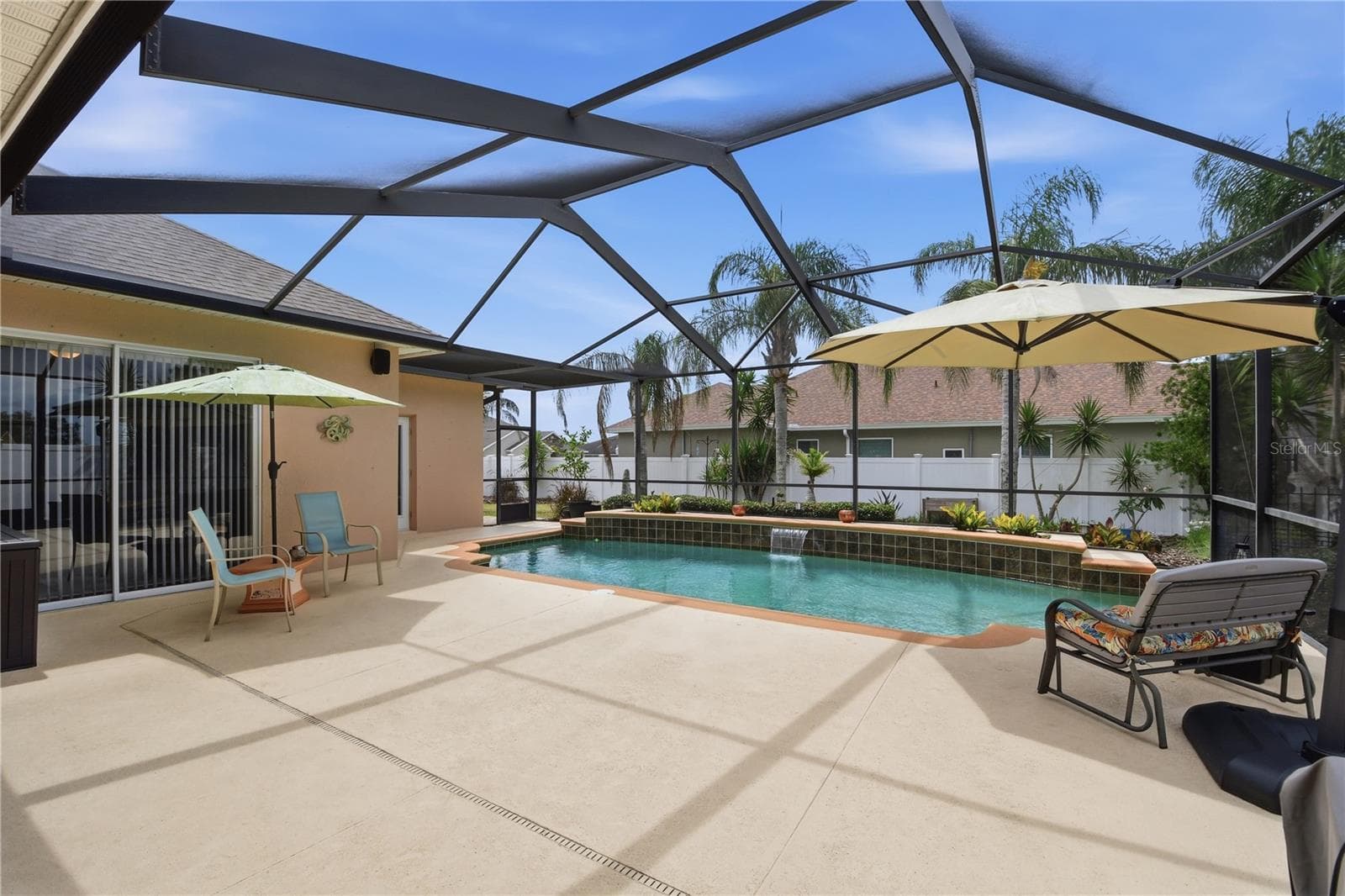 Screened Pool – Spacious screened pool area with a generous deck, tropical landscaping, and a raised water feature that creates an inviting outdoor setting. - 114 VIOLA DR, AUBURNDALE