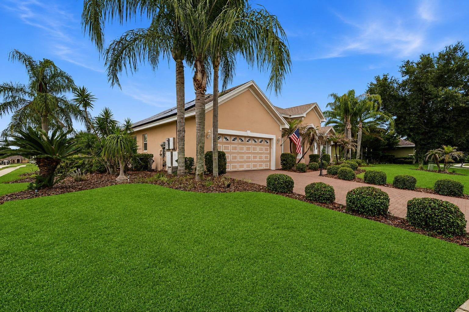 Front Exterior / Garage View – A second exterior angle highlights the attached two-car garage, brick-paver driveway, and thoughtfully maintained tropical landscaping surrounding the home. - 114 VIOLA DR, AUBURNDALE