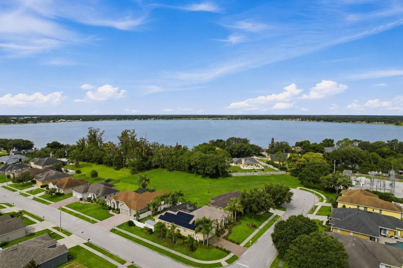 Aerial / Neighborhood View – Wide aerial perspective highlights the surrounding residential setting, mature greenery, and a large nearby lake. - 114 VIOLA DR, AUBURNDALE