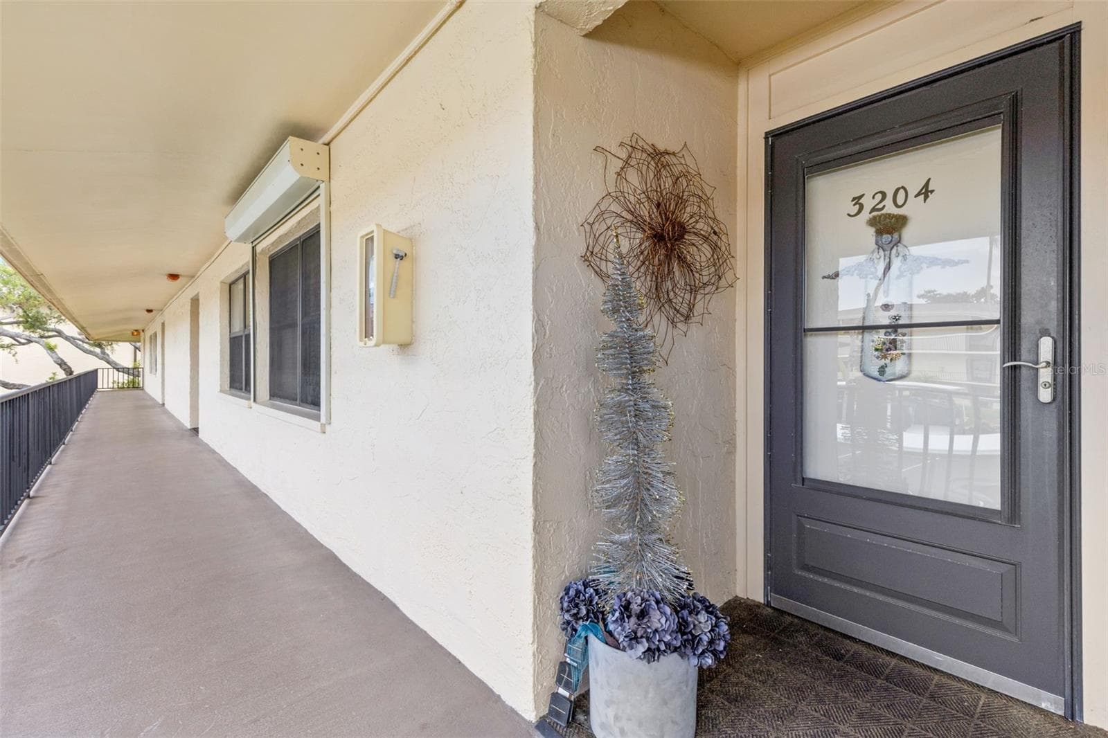A covered second-floor walkway leads to the unit’s front entry, set along an open-air corridor with railing views across the community. - 12300 VONN RD #3204, LARGO