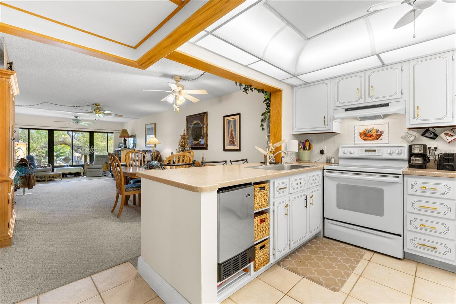 The kitchen opens directly to the dining and living areas, with a generous peninsula providing extra prep space and a clear sightline through the main living area. Ceramic tile, abundant cabinetry and a tray-style ceiling round out the space. - 12300 VONN RD #3204, LARGO