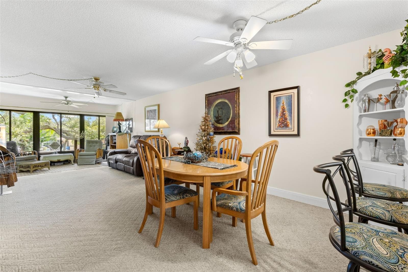 The dining area sits between the kitchen and living room, creating a long, open main living space with plenty of room to define each area. A wall of windows at the far end brings in natural light and looks out toward the trees and landscaped grounds. - 12300 VONN RD #3204, LARGO