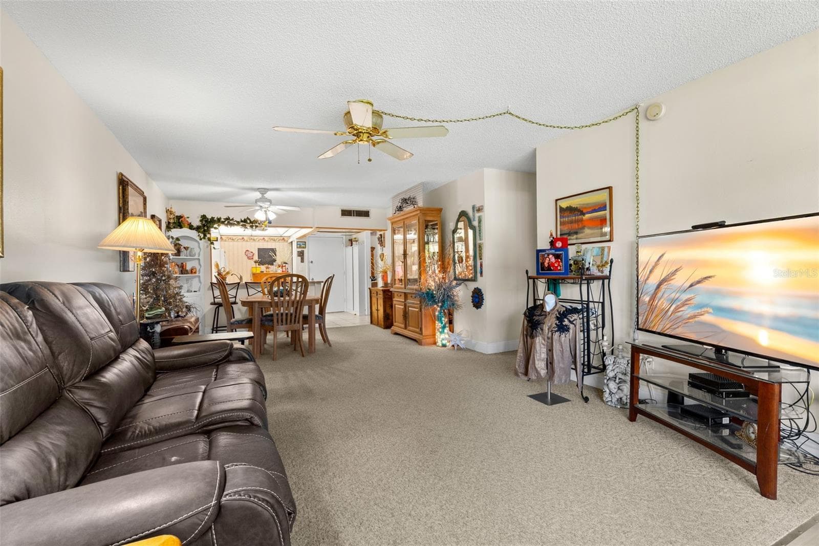 The main living area runs in one continuous line from the living room through the dining space to the kitchen, giving each area its own place without closing them off from one another. Neutral carpeting and ceiling fans continue throughout the shared living space. - 12300 VONN RD #3204, LARGO