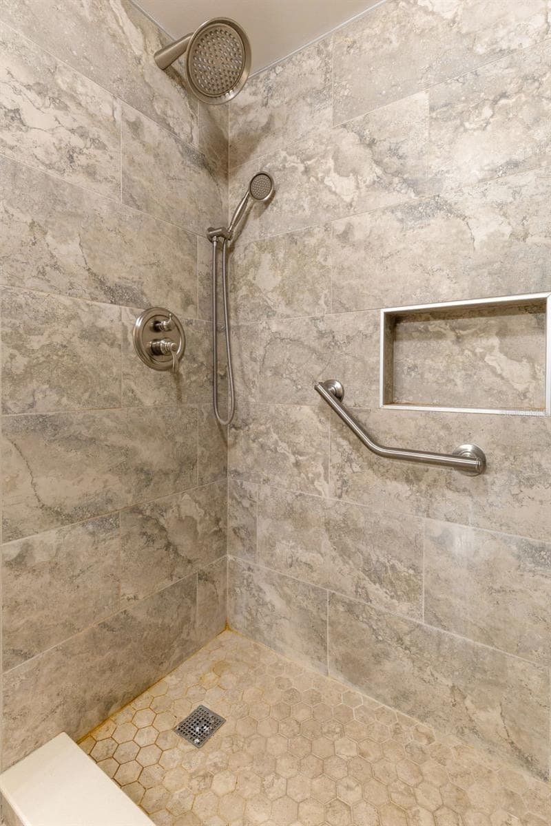The walk-in shower is finished with large-format wall tile and a hex-pattern tile floor, with both fixed and handheld showerheads, a recessed niche and a grab bar built into the space. - 12300 VONN RD #3204, LARGO