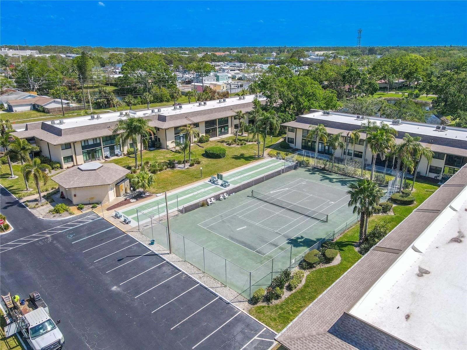 The recreation area includes a full tennis court with adjacent shuffleboard courts, set among palms and landscaped grounds near the center of the community. - 12300 VONN RD #3204, LARGO