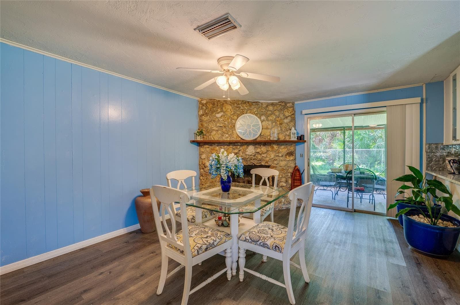 Inviting space highlighted by a floor-to-ceiling stone fireplace, light blue paneling, LVP flooring, and direct sliding glass door access to the back patio. - 146 WESTWOOD DR, DAYTONA BEACH