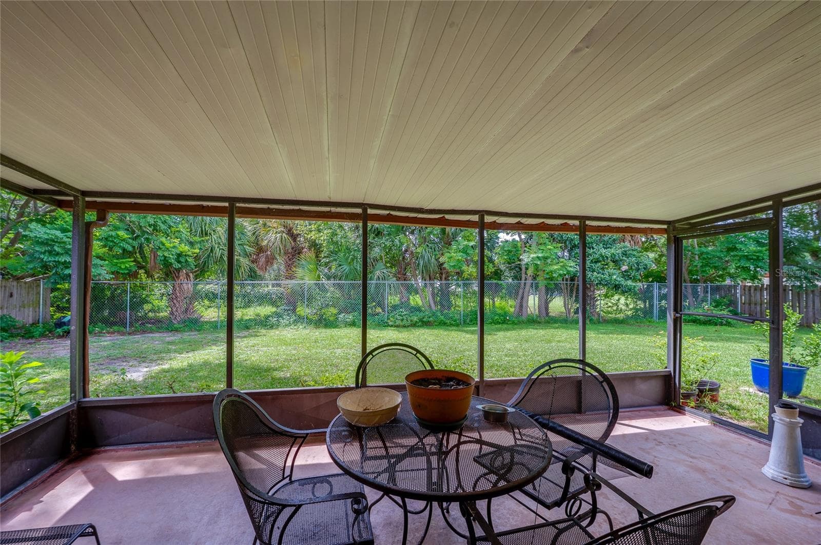 Screened-in back porch providing full views of the green backyard and surrounding tree line. - 146 WESTWOOD DR, DAYTONA BEACH
