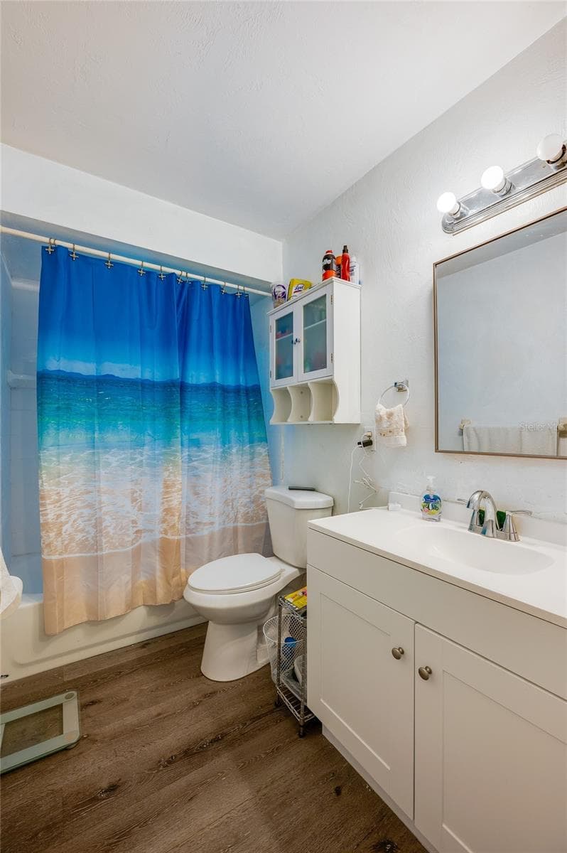 Full bathroom with a white vanity, mirrored medicine cabinet, and LVP flooring. - 146 WESTWOOD DR, DAYTONA BEACH