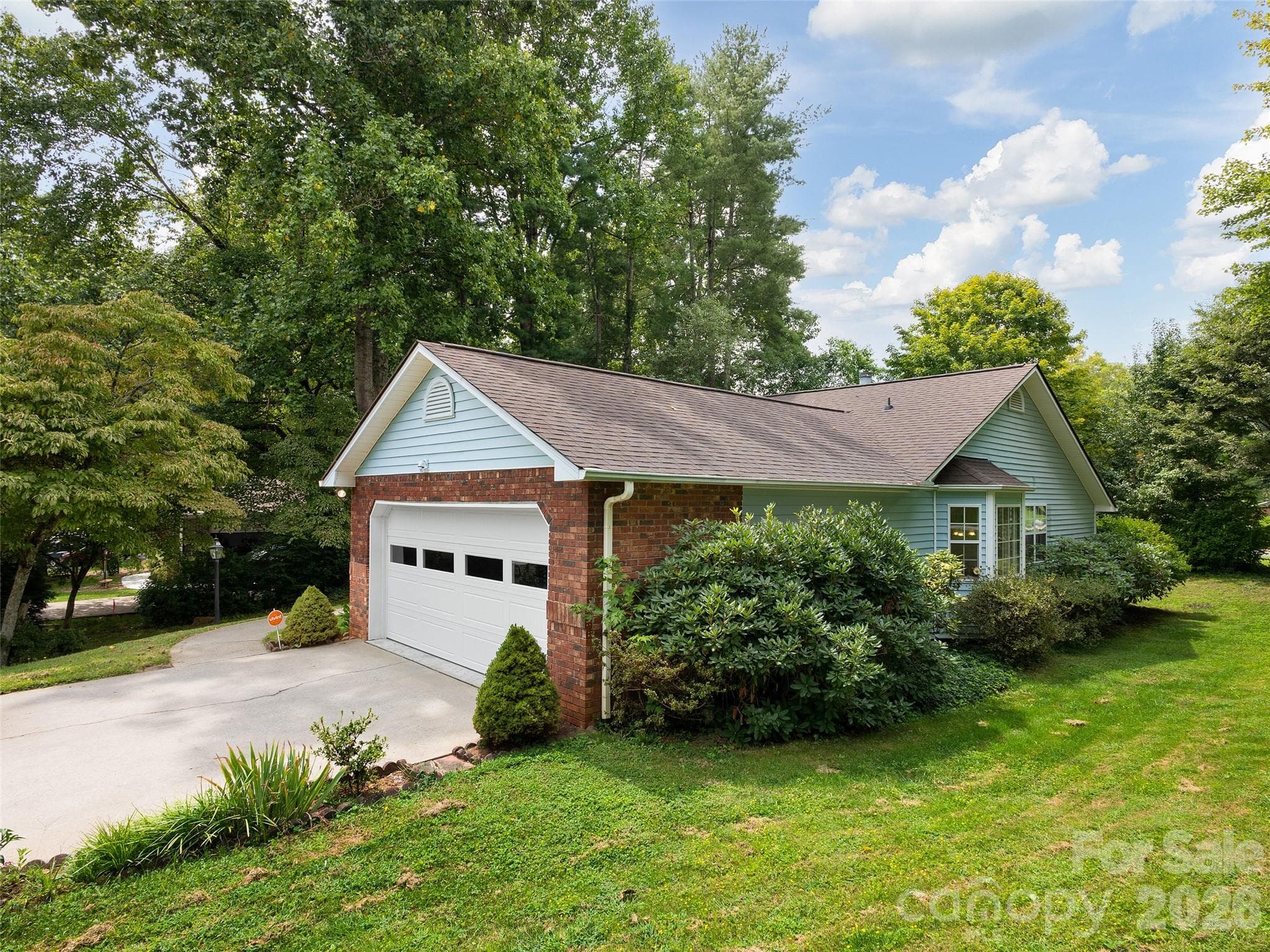 Beautiful exterior view of this Etowah, NC home featuring mature landscaping, a spacious yard, concrete driveway, and attached two-car garage. - 5 St Andrews Drive, Etowah
