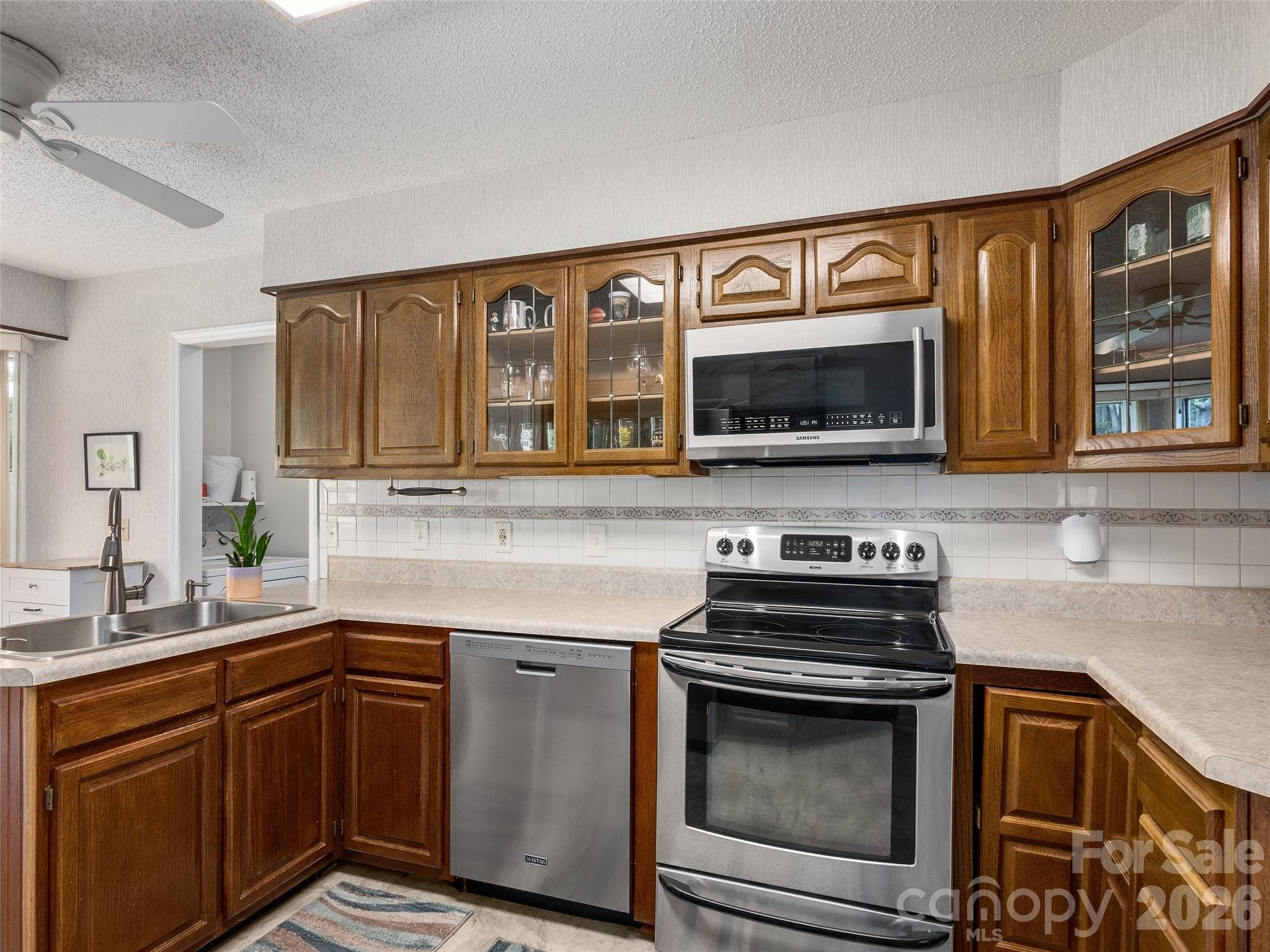 Well-designed kitchen with wood cabinetry and included appliances at this Etowah, NC home - 5 St Andrews Drive, Etowah