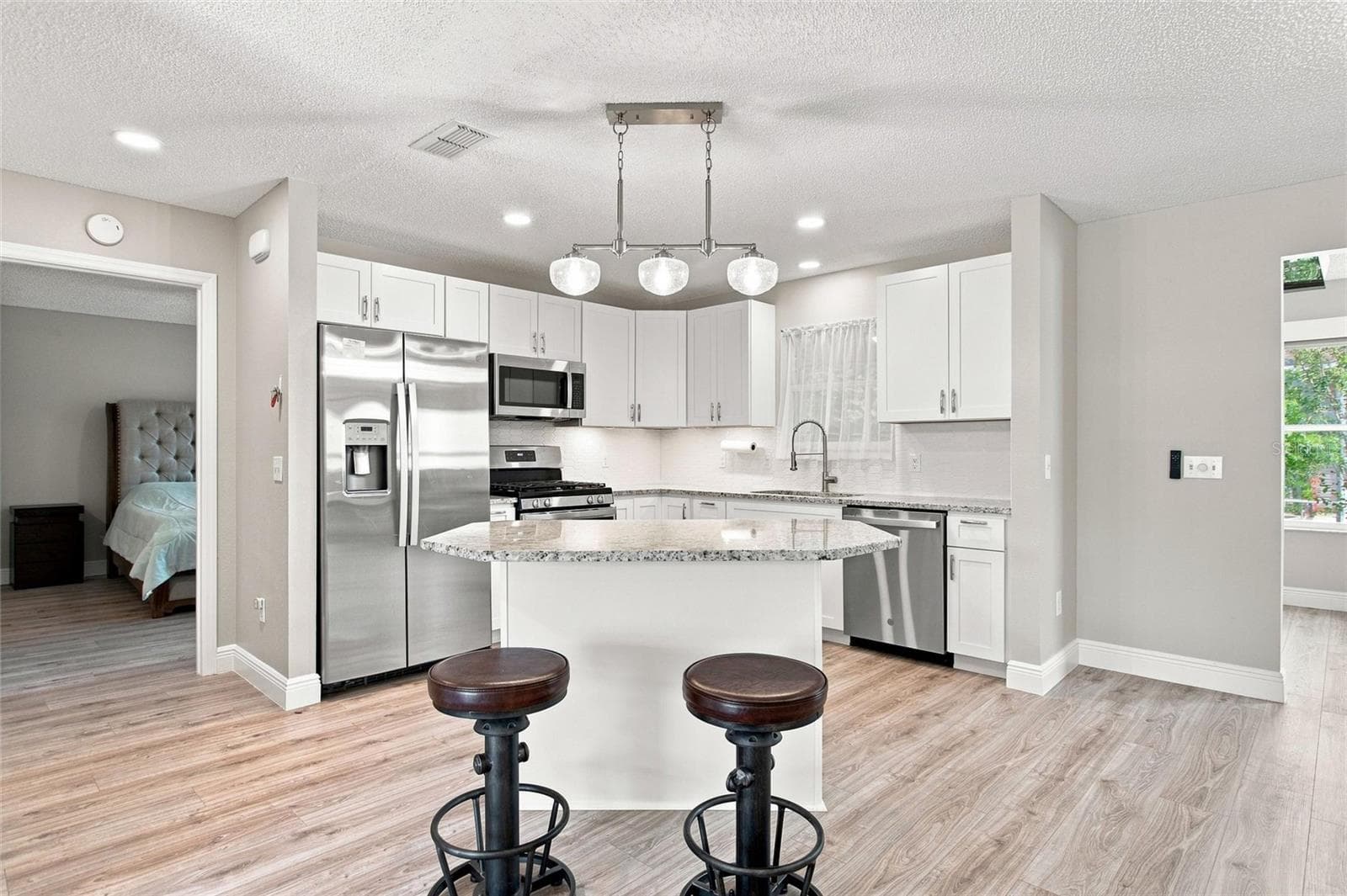 Kitchen updated in 2024 with white cabinetry, granite countertops and stainless steel appliances. - 2713 DE LA ROSA ST, THE VILLAGES
