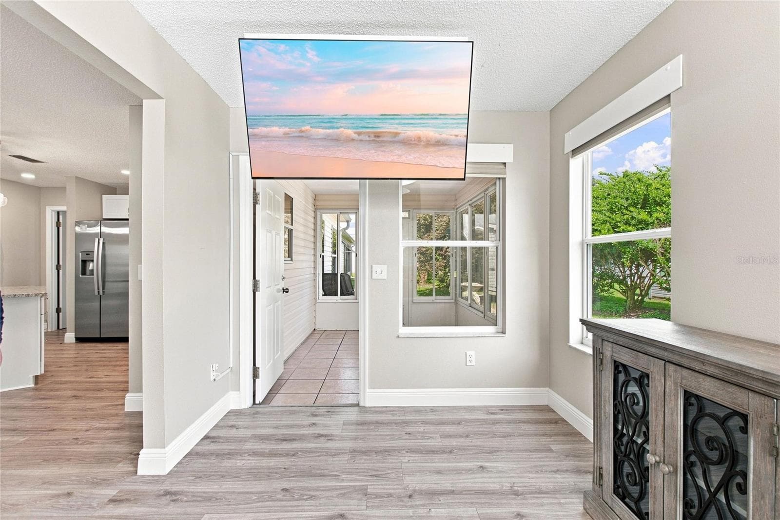 Large windows frame views of the backyard greenery from this versatile Florida room. - 2713 DE LA ROSA ST, THE VILLAGES