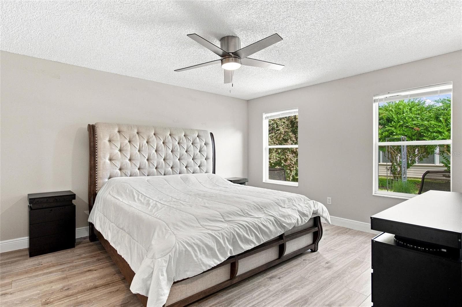 Bright primary bedroom with two windows, a ceiling fan and luxury vinyl plank flooring. - 2713 DE LA ROSA ST, THE VILLAGES