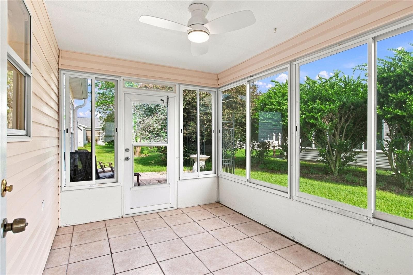 Enclosed lanai with tile flooring and backyard views offers a bright place to relax. - 2713 DE LA ROSA ST, THE VILLAGES