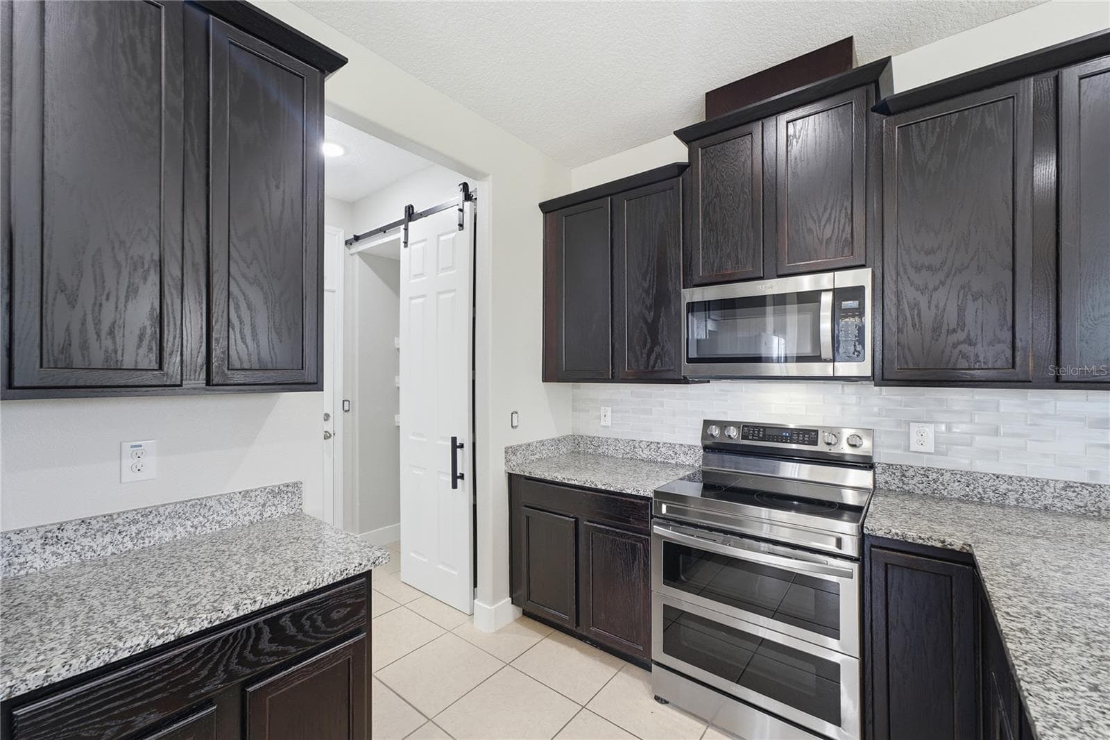 Stylish kitchen with granite countertops, subway-tile backsplash, abundant cabinetry and stainless steel appliances. - 2615 GIARDINO LOOP, KISSIMMEE
