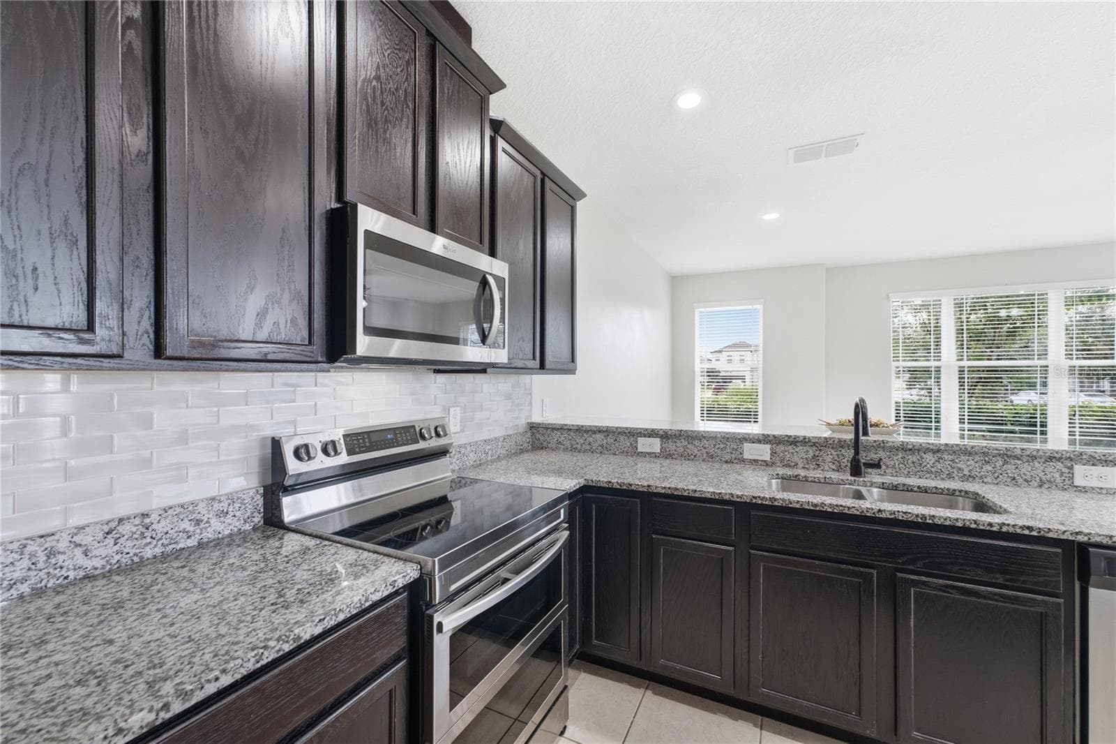 Granite countertops, subway-tile backsplash and stainless steel appliances complete this stylish kitchen. - 2615 GIARDINO LOOP, KISSIMMEE