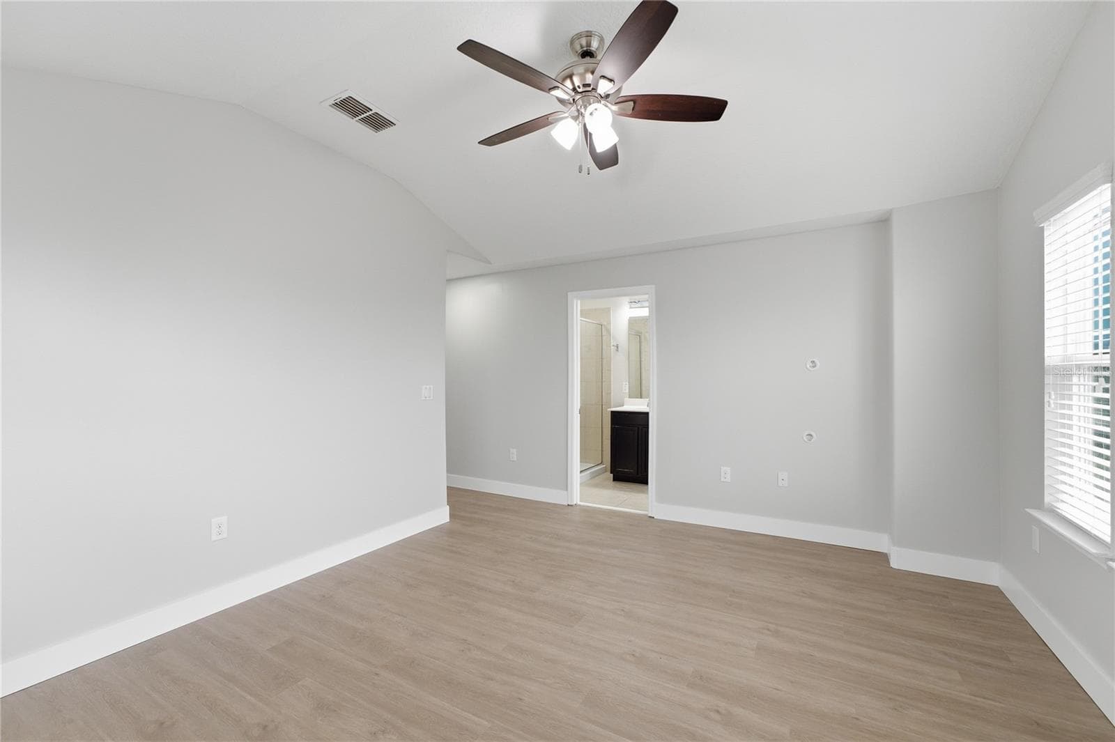 Spacious primary bedroom with a vaulted ceiling, vinyl plank flooring and private en-suite bathroom. - 2615 GIARDINO LOOP, KISSIMMEE