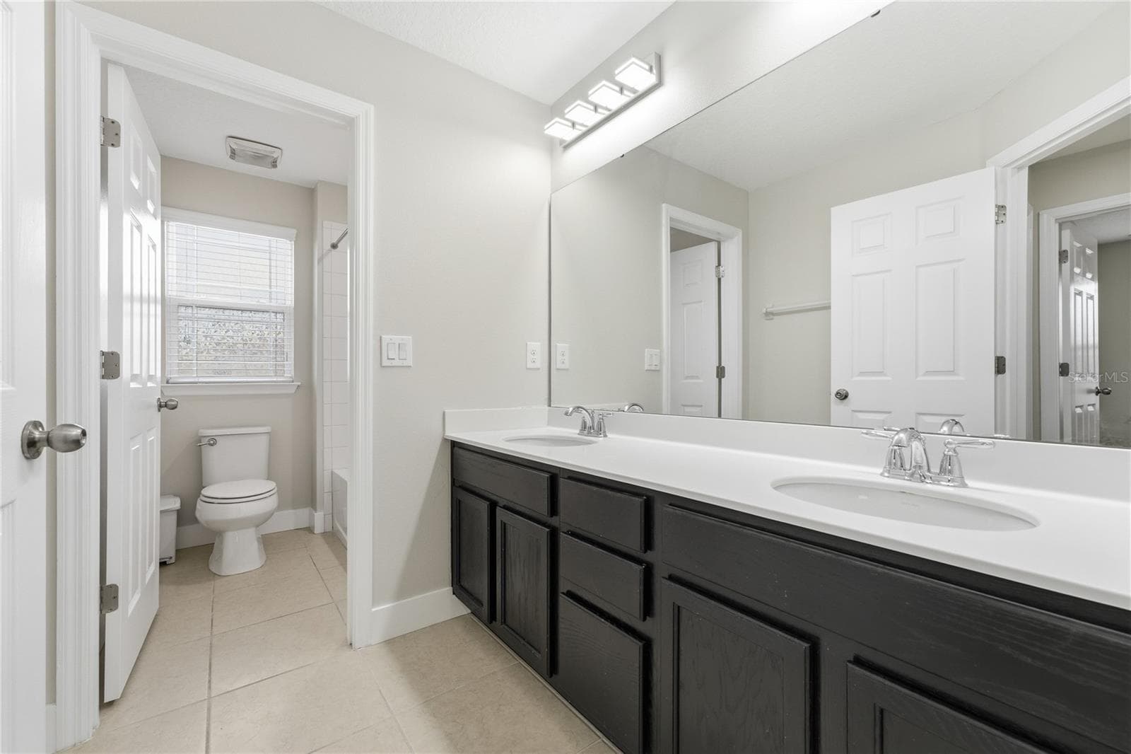 Upstairs hall bathroom featuring a spacious dual-sink vanity and private tub-and-shower area. - 2615 GIARDINO LOOP, KISSIMMEE