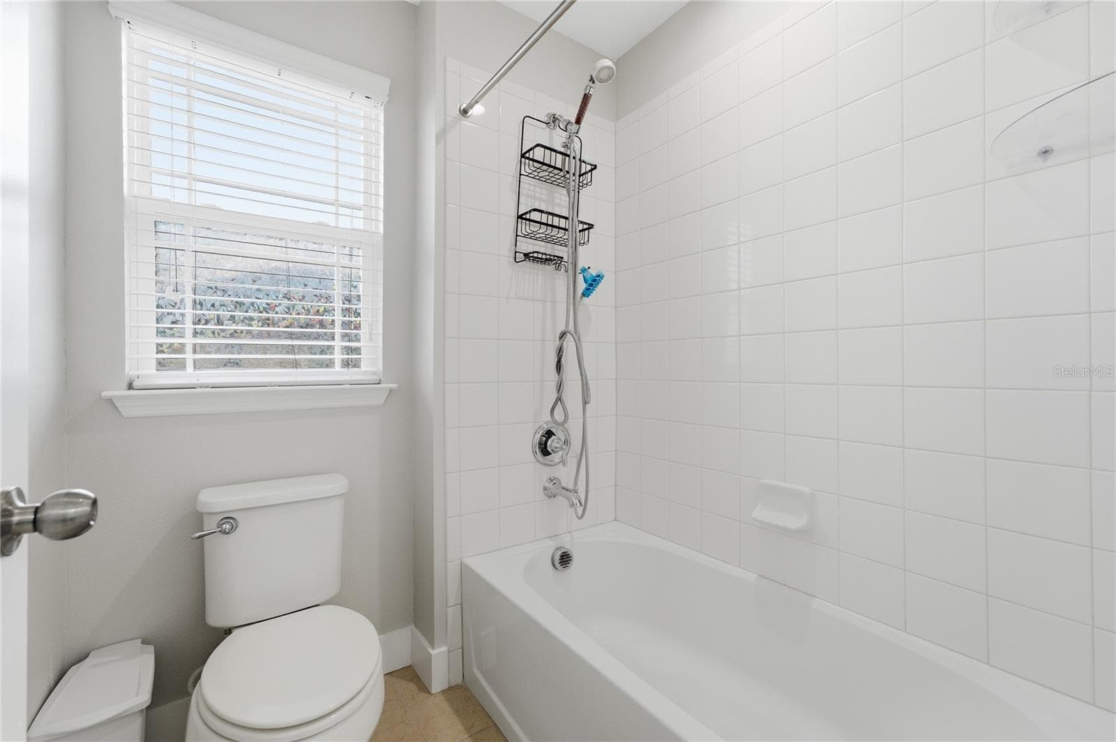 Second full bathroom upstairs featuring a tiled tub-and-shower combination and natural light. - 2615 GIARDINO LOOP, KISSIMMEE