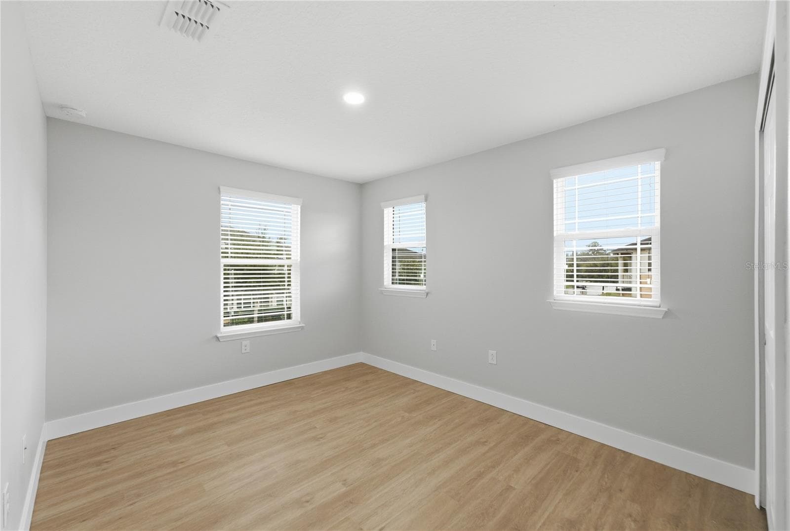 Bright third bedroom with vinyl plank flooring and abundant natural light from three windows. - 2615 GIARDINO LOOP, KISSIMMEE