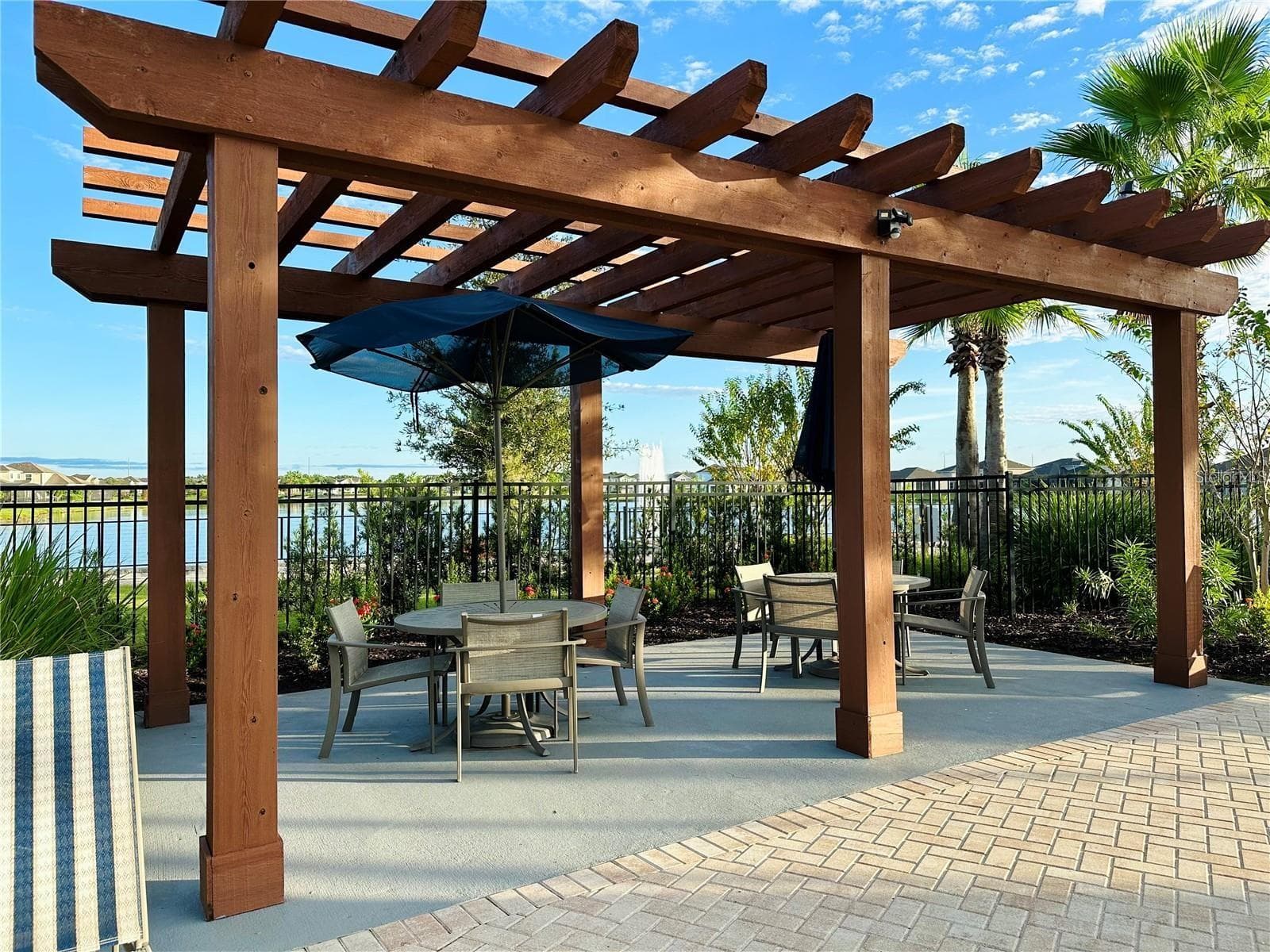 Shaded poolside pergola with comfortable seating and peaceful lake views. - 2615 GIARDINO LOOP, KISSIMMEE