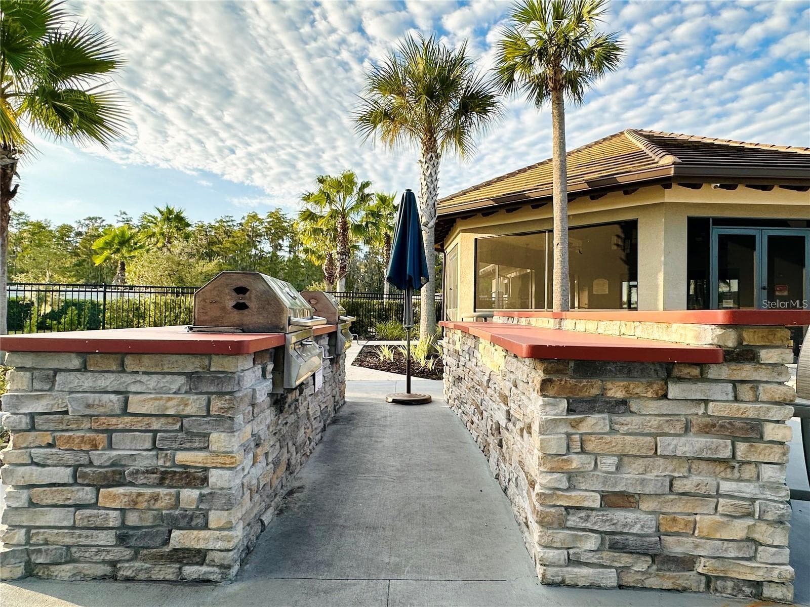 Community outdoor grilling station with convenient counter space and nearby covered seating. - 2615 GIARDINO LOOP, KISSIMMEE