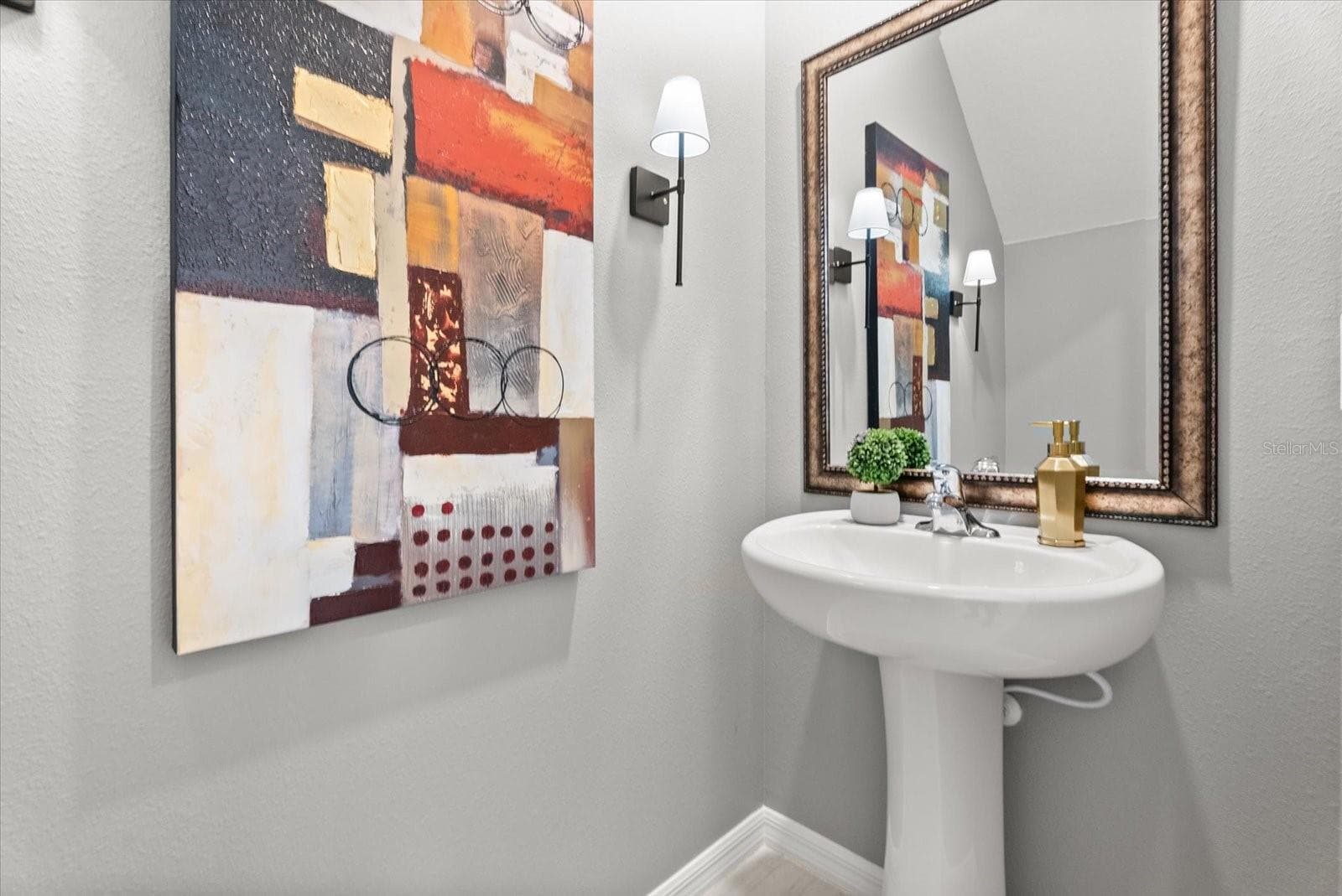 Stylish first-floor powder room with pedestal sink and framed mirror. - 8431 BELLA MAR TRL, PARRISH