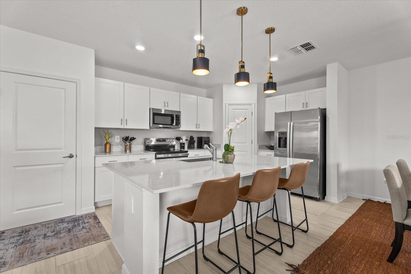 Modern kitchen with a large center island, breakfast seating, and pendant lighting. - 8431 BELLA MAR TRL, PARRISH