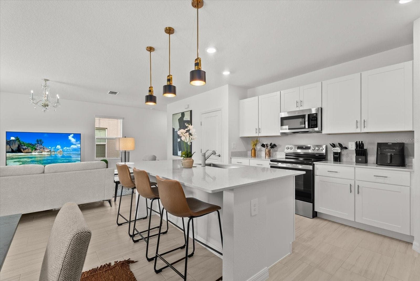Open kitchen featuring white cabinetry, stone countertops, and stainless-steel appliances. - 8431 BELLA MAR TRL, PARRISH