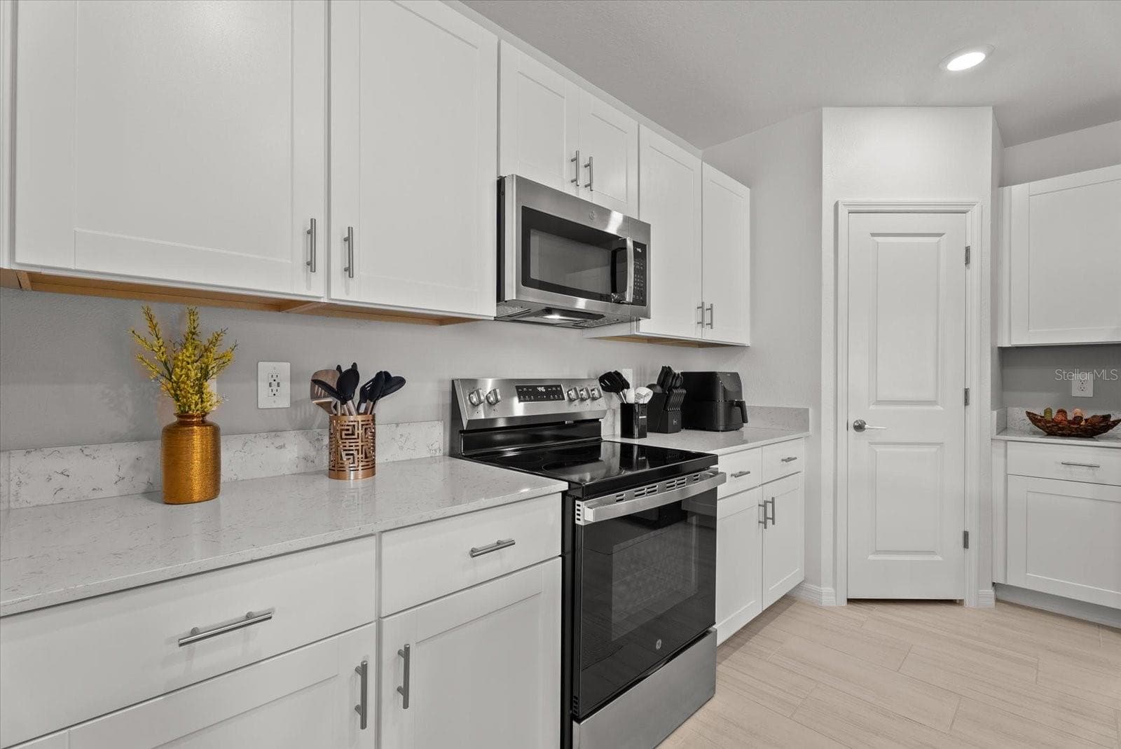 Sleek stainless-steel range and microwave surrounded by bright white cabinetry. - 8431 BELLA MAR TRL, PARRISH