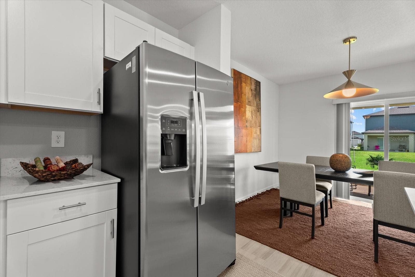 Stainless-steel refrigerator with the adjoining dining area and backyard view. - 8431 BELLA MAR TRL, PARRISH