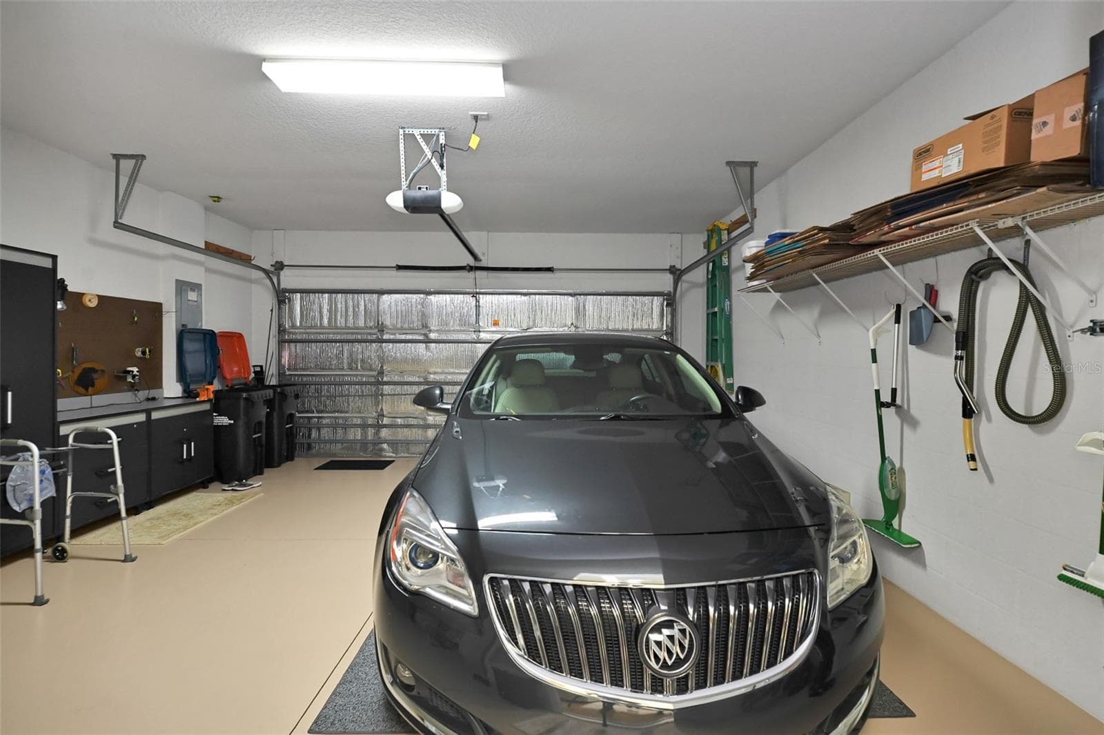 2 car garage with epoxy floor, insulated garage door, full screen, workbench, cabinets, garage door opener, water softener, water heater & installed storage racks - 7139 SW 91ST CT, OCALA