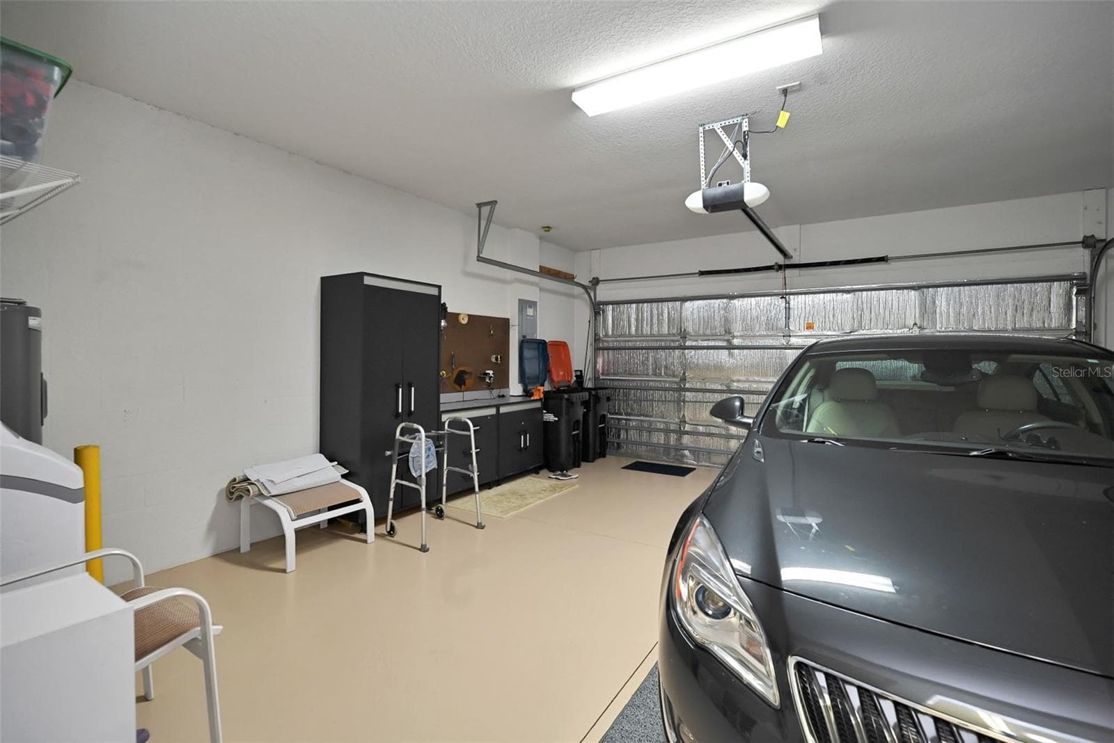2 car garage with epoxy floor, insulated garage door, full screen, workbench, cabinets, garage door opener, water softener, water heater & installed storage racks - 7139 SW 91ST CT, OCALA