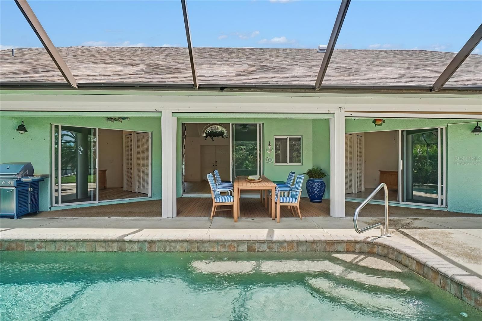 Under Truss area showing all 3 sets of pocket sliders overlooking the pool - Virtually Staged - 405 POINSETTIA AVE, LEHIGH ACRES