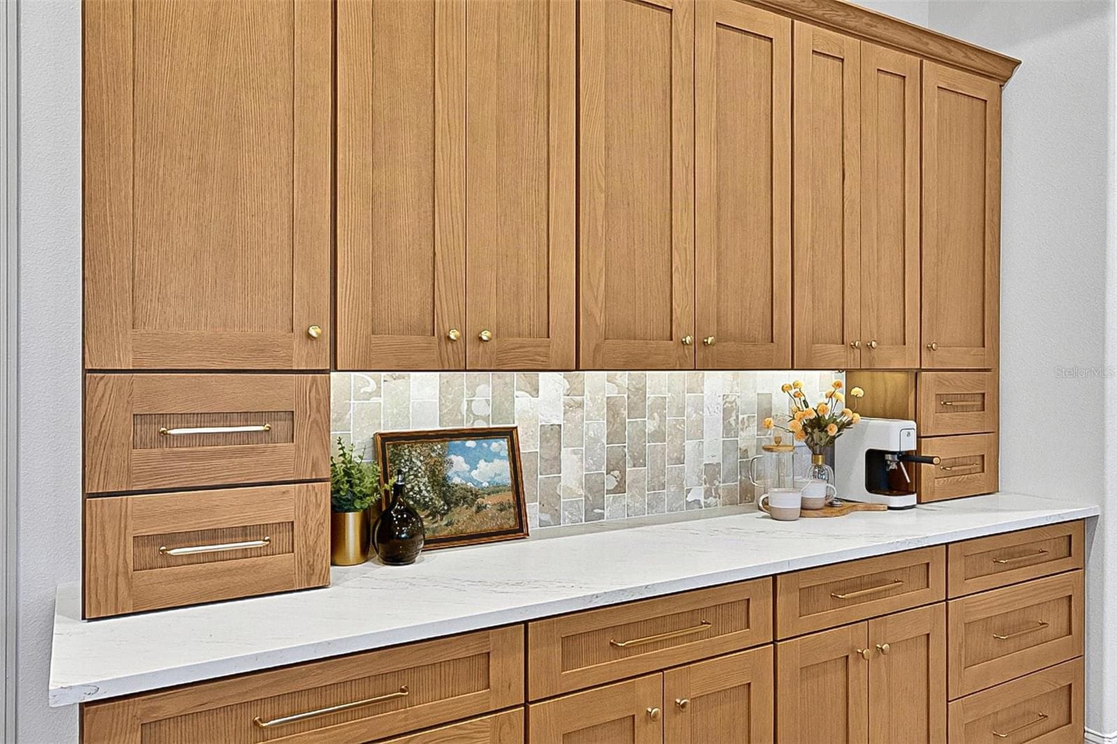 Full wall of Custom Wood soft close cabinets with under-mount lighting against the stunning tile and quartz countertops - 17 GRANDVIEW DR, PALM COAST