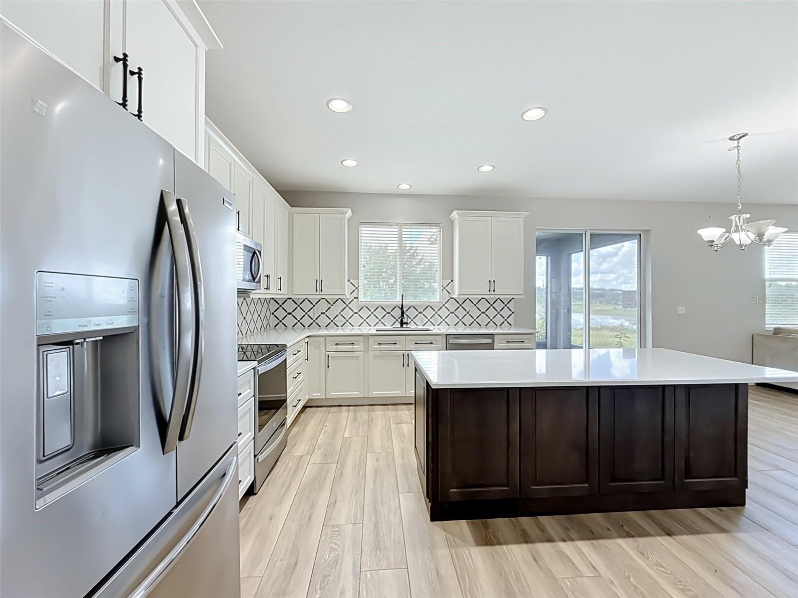 Kitchen showing stainless refrigerator, island and dining area - 852 N JACKS LAKE RD, CLERMONT