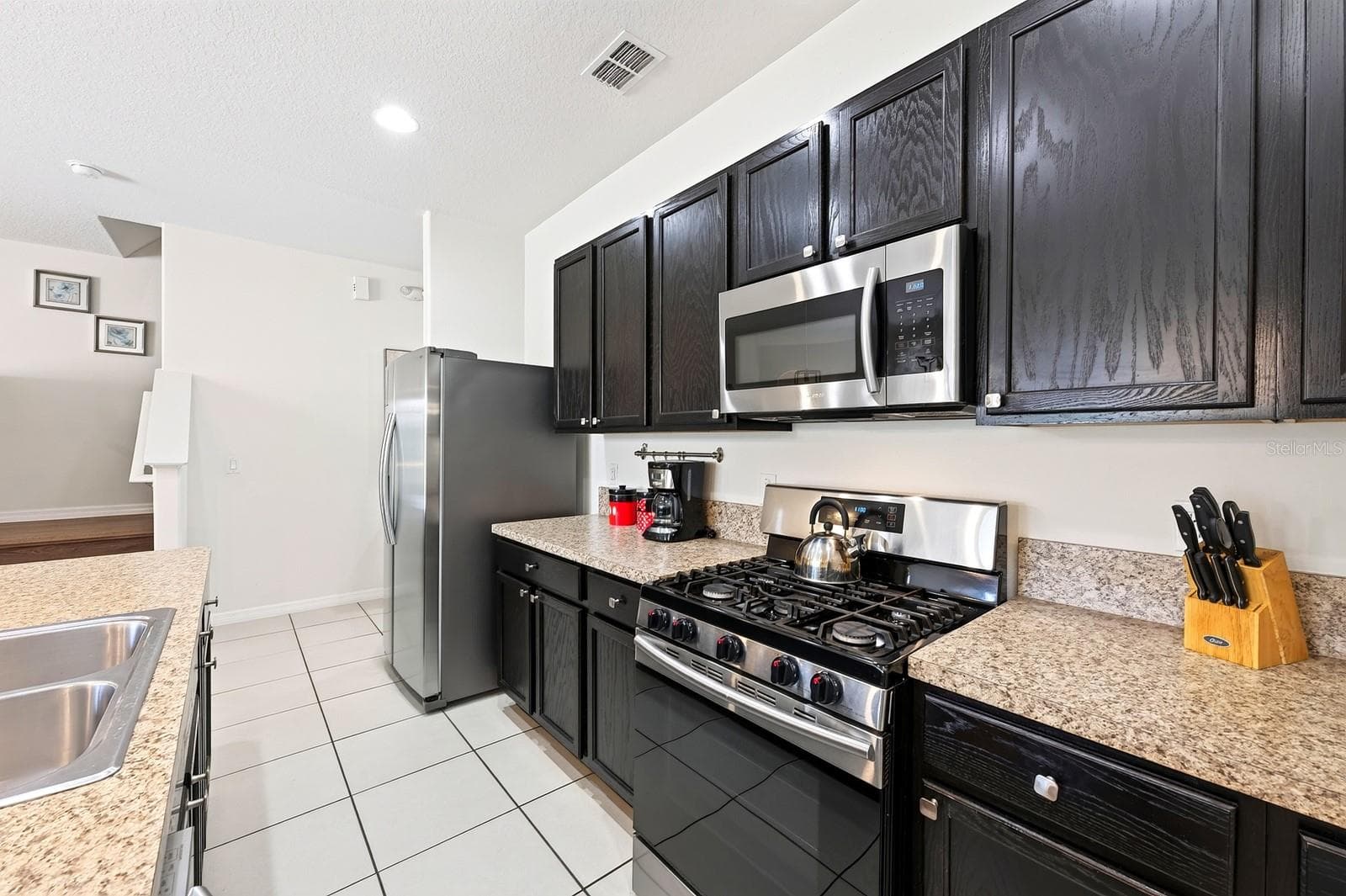 The well-appointed Kitchen features plenty of cabinet and counter space, a large ISLAND WITH BREAKFAST BAR SEATING and STAINLESS STEEL APPLIANCES, including a GAS STOVE. - 4722 TERRASONESTA DR, DAVENPORT
