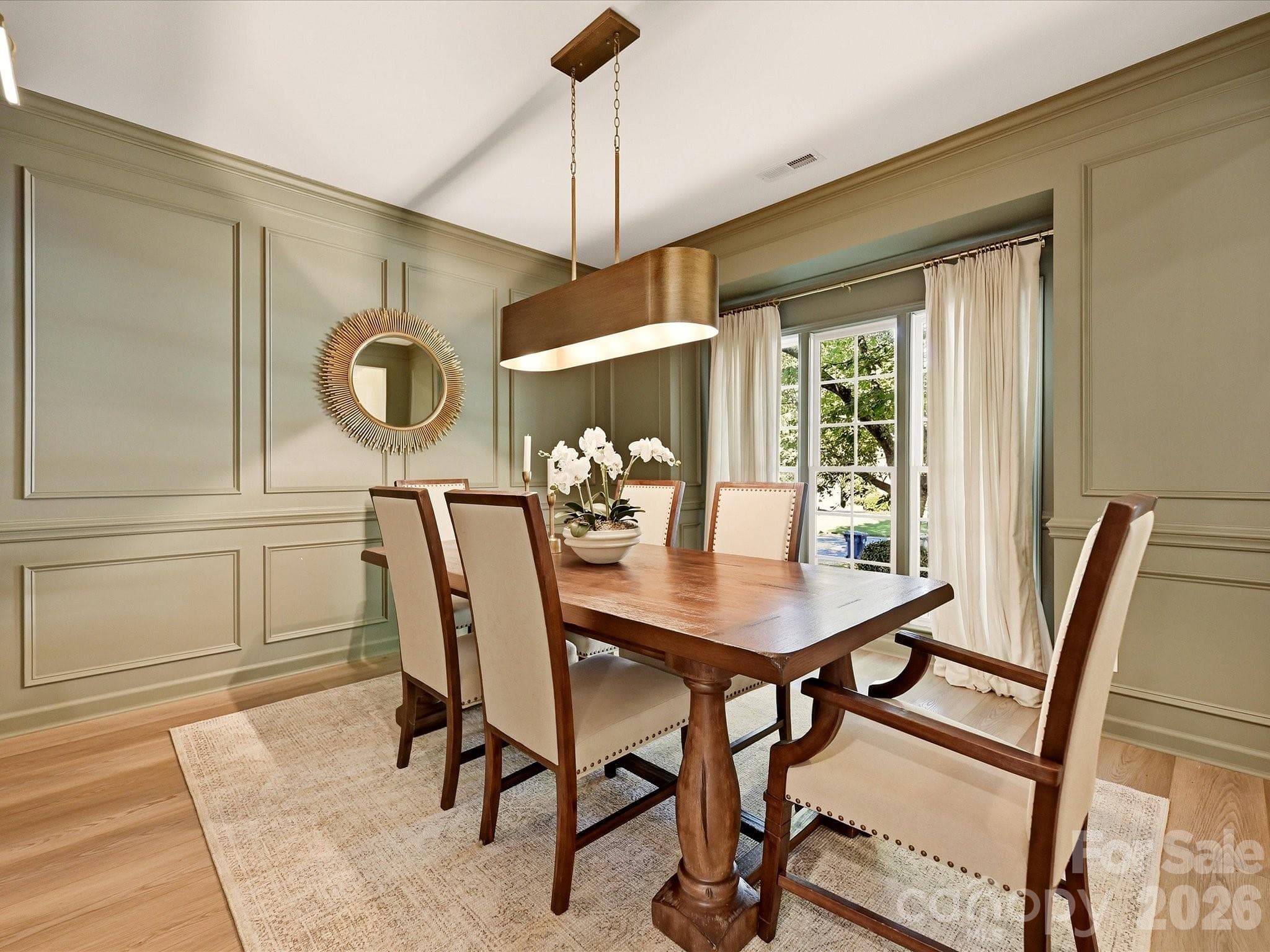 Elegant formal dining room showcases decorative wall molding, wood-look vinyl plank flooring, abundant natural light, and a stylish modern light fixture. - 19706 Valiant Way, Cornelius