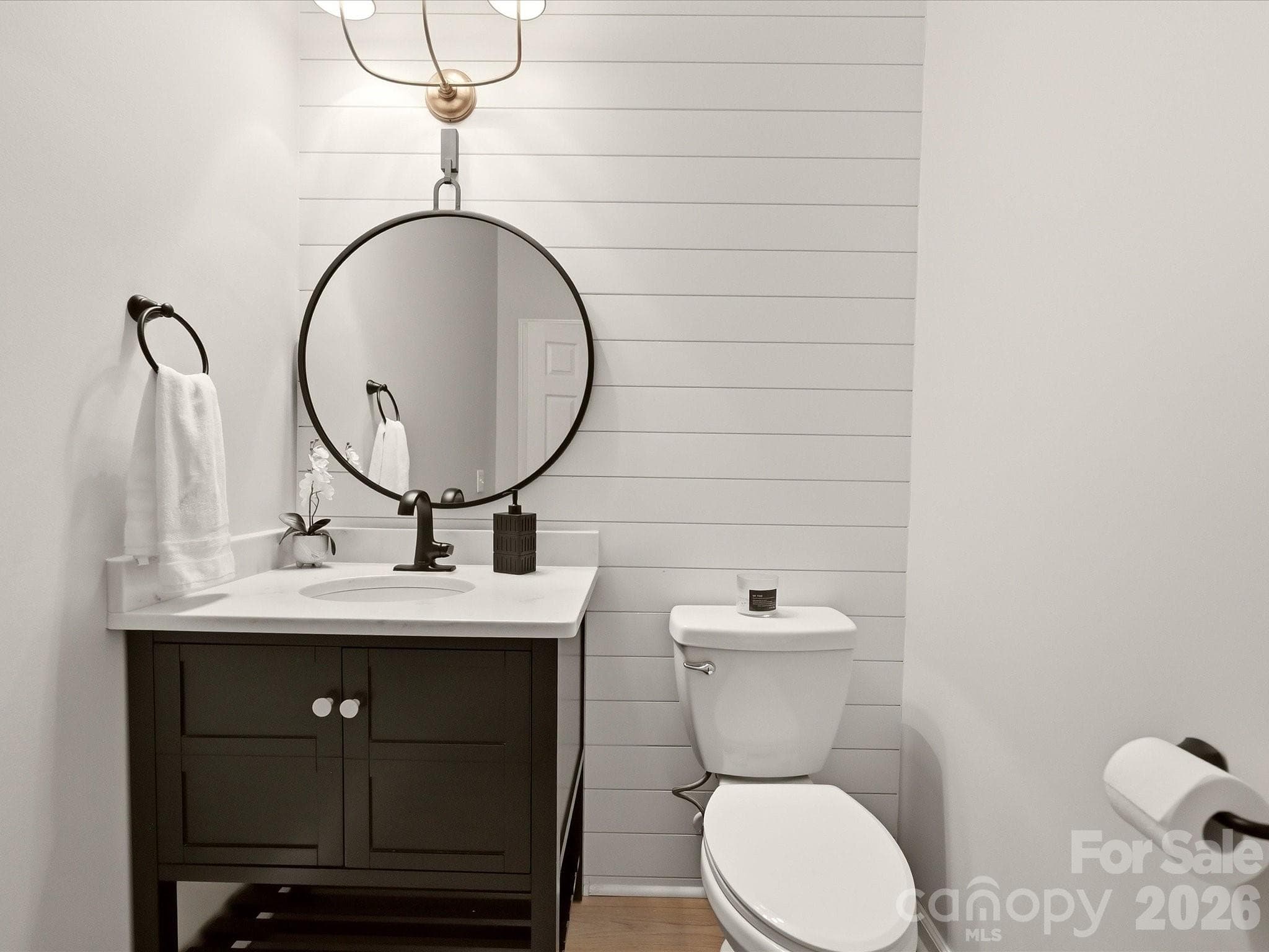 Updated main-level powder room features a modern vanity, shiplap accent wall, and contemporary finishes. - 19706 Valiant Way, Cornelius
