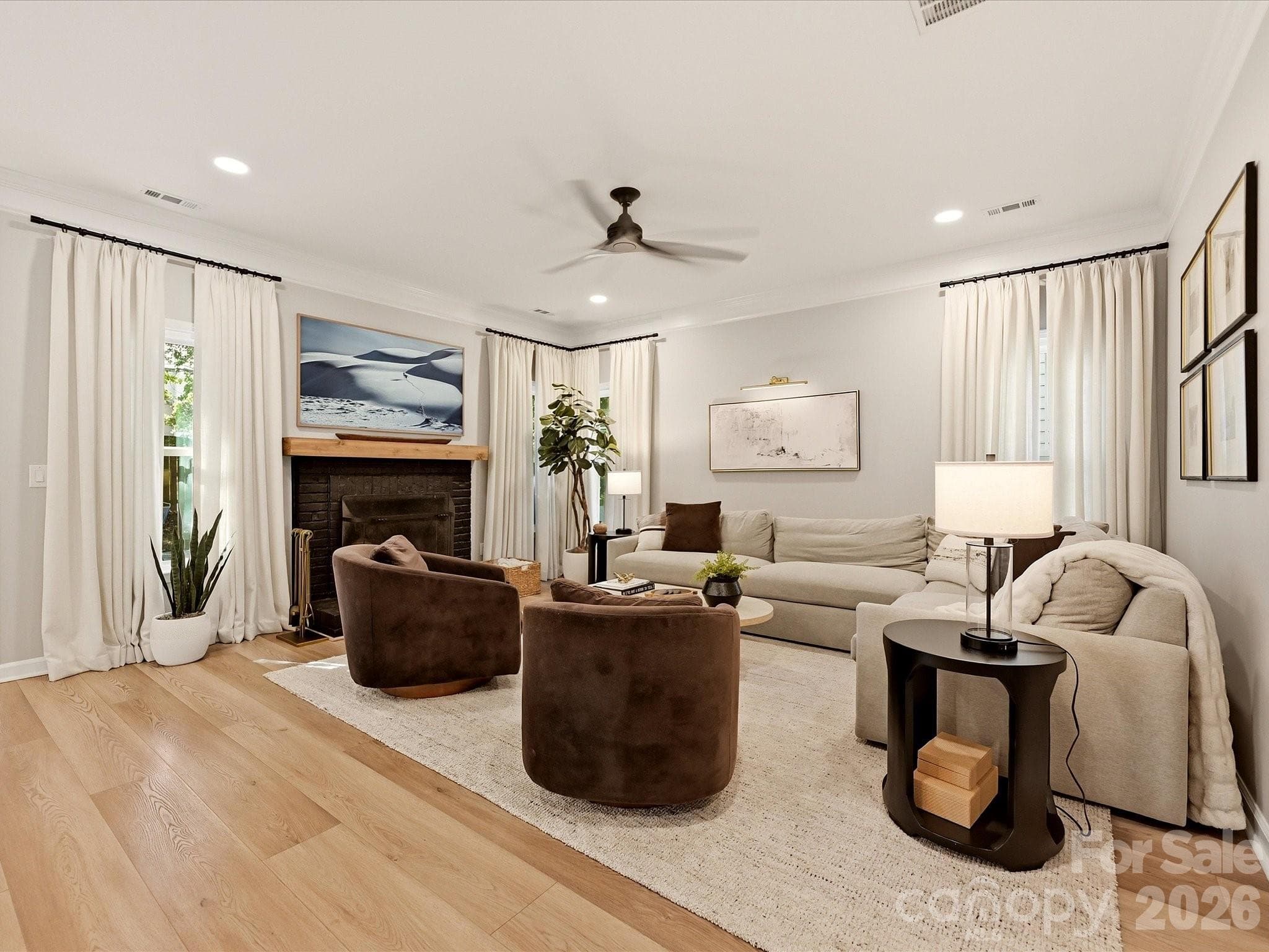 Spacious living room features a wood-burning fireplace, wood-look vinyl plank flooring, abundant natural light, and an inviting open-concept design. - 19706 Valiant Way, Cornelius