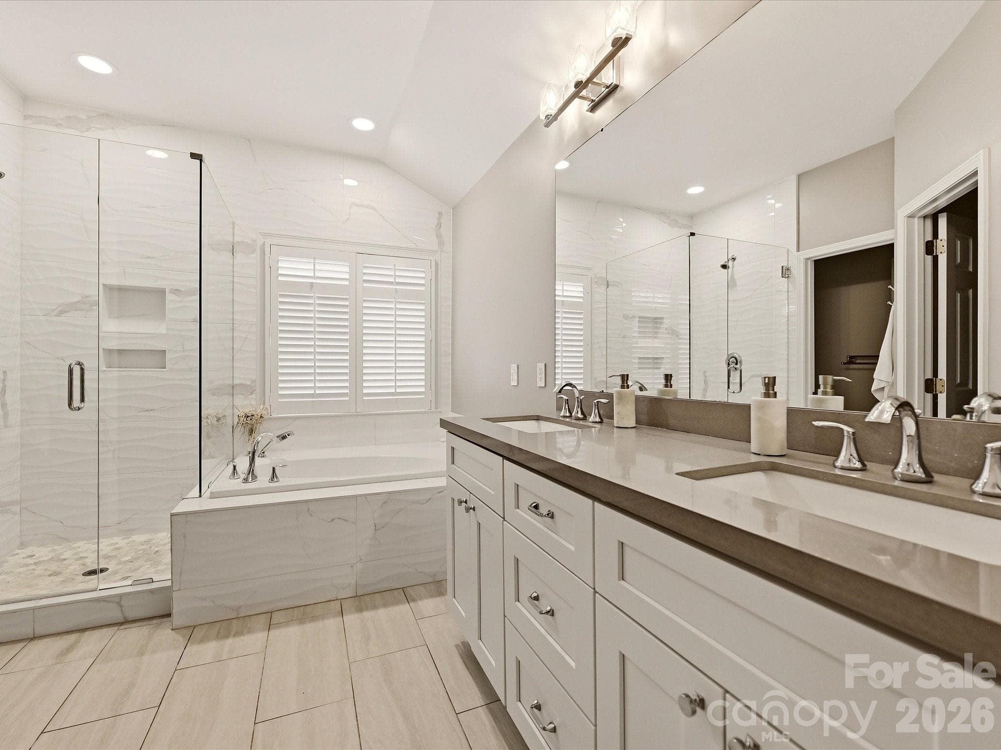 Primary bathroom features a dual-sink vanity, soaking tub, separate glass-enclosed shower, and spacious layout. - 19706 Valiant Way, Cornelius