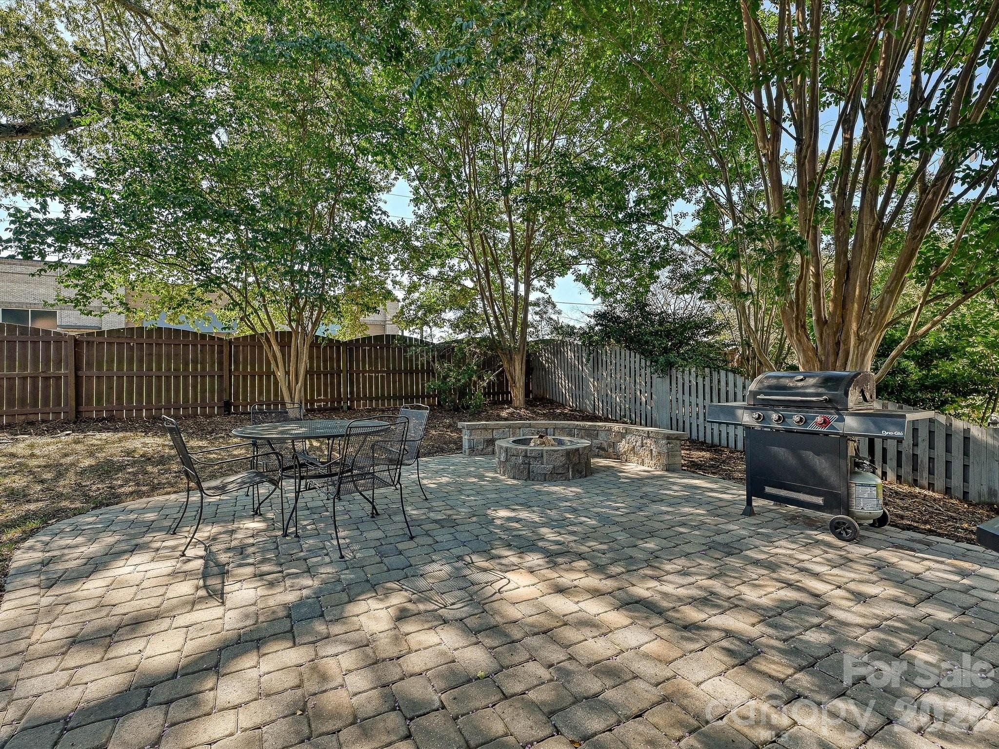 Large backyard patio creates an inviting outdoor entertaining area surrounded by trees and a fenced yard. - 19706 Valiant Way, Cornelius