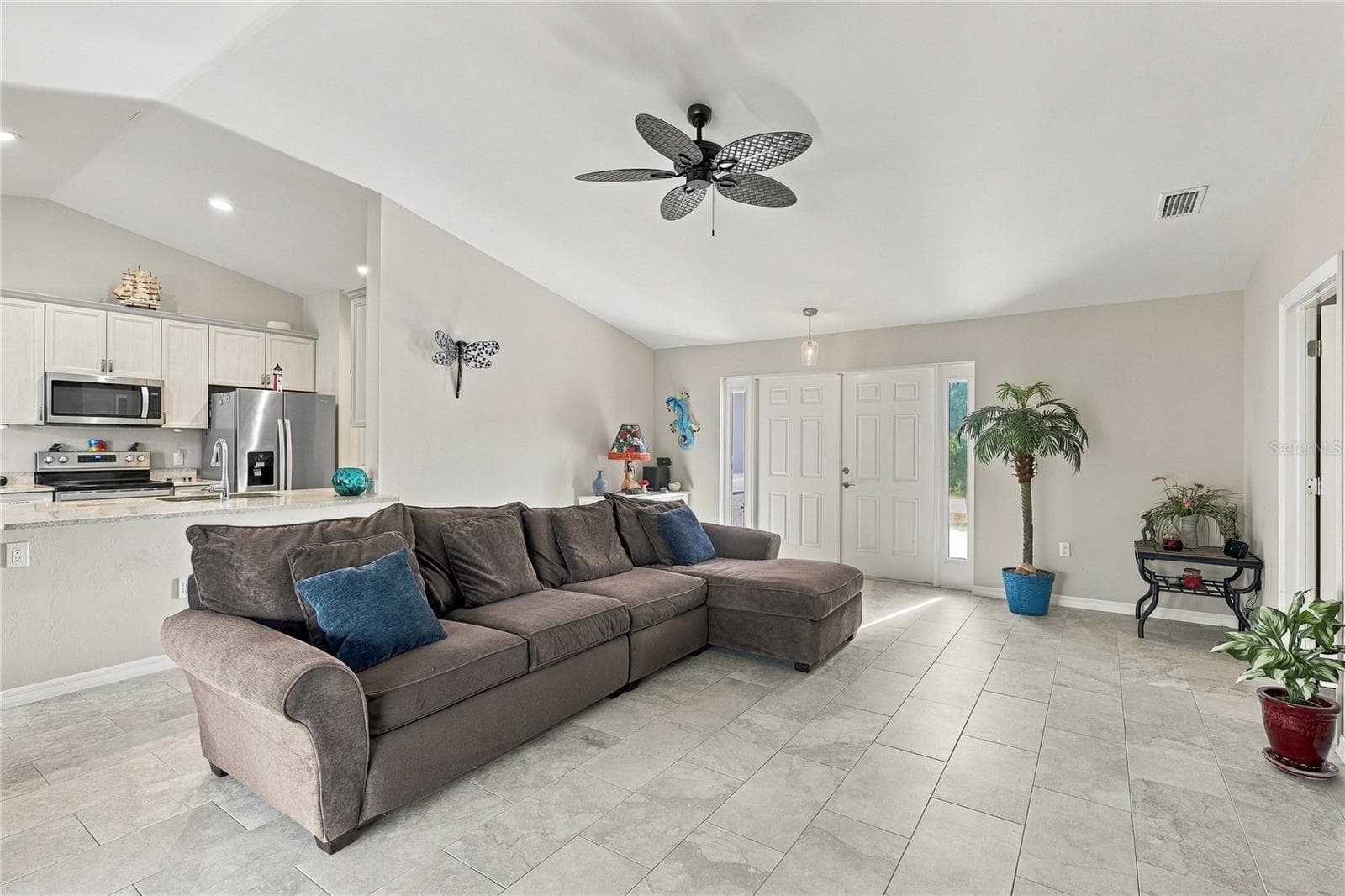 LIVING ROOM OVERLOOKING KITCHEN. TILE, GRANITE, STAINELSS STEEL, UPGRADED CEILING FAN MAKES FOR A COMFORTABLE AREA TO LIVE IN - 10554 LIVE OAK RD, PORT CHARLOTTE