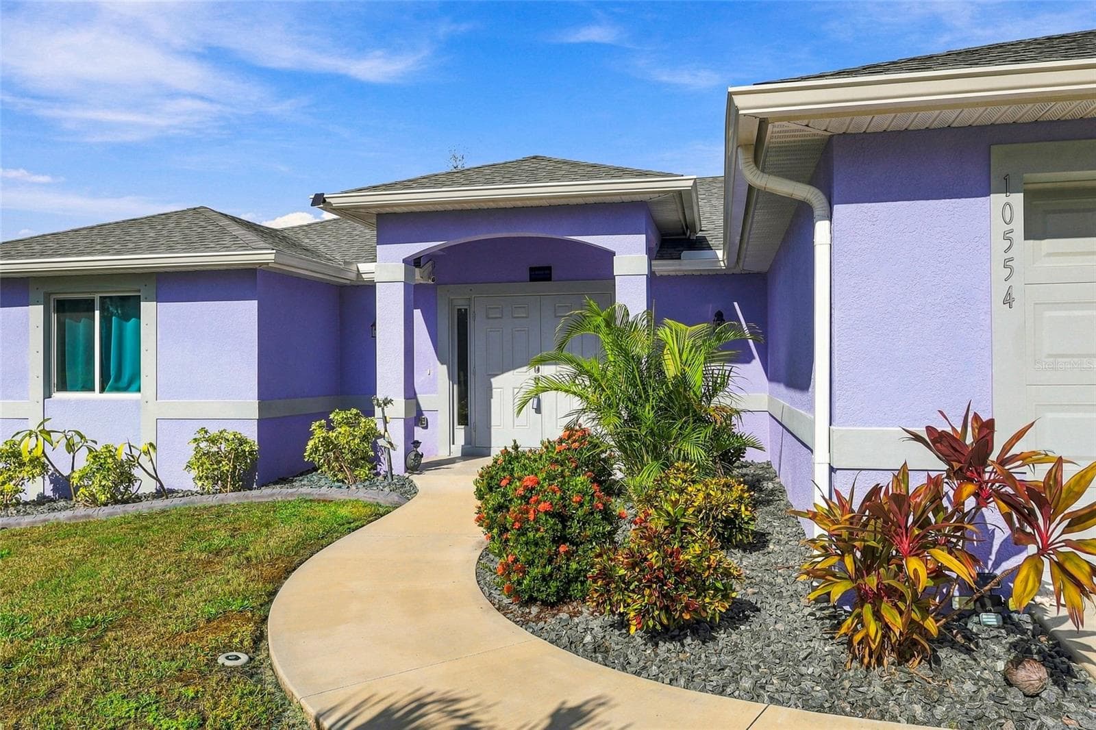 CONCRETE CURBING AND GREY ROCK SURROUND THE LUSH FLORIDA LANDSCAPING - 10554 LIVE OAK RD, PORT CHARLOTTE