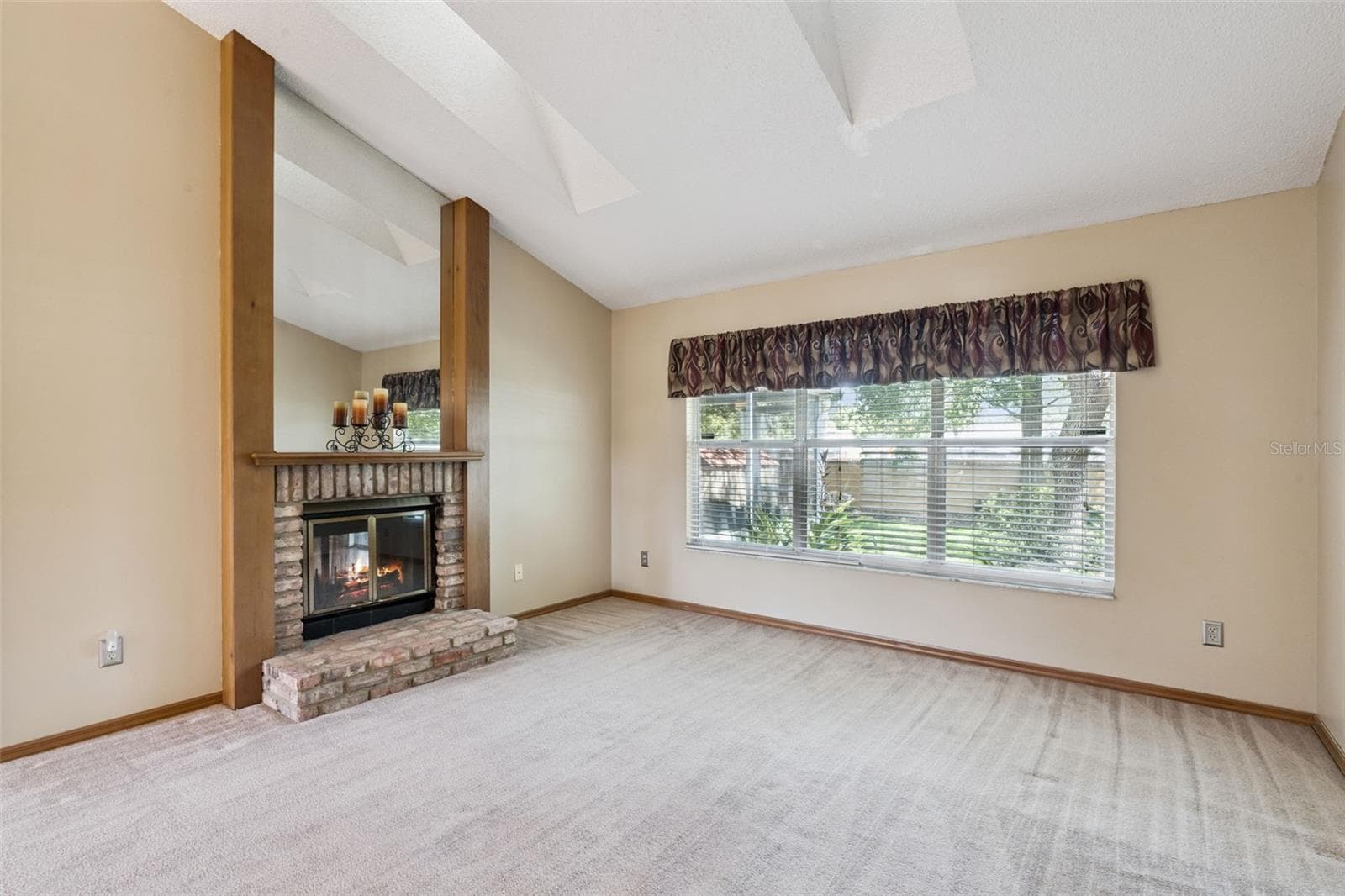 Inviting living room with double-sided brick fireplace, skylights and a peaceful backyard view - 288 RINGWOOD DR, WINTER SPRINGS