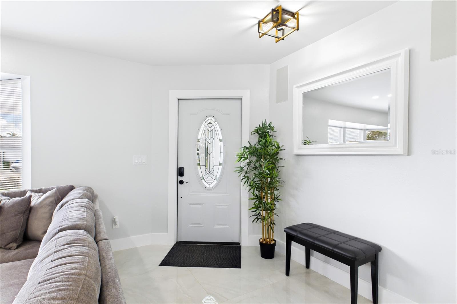 Bright & welcoming entry showcases a decorative glass front door, contemporary lighting, crisp neutral finishes & polished porcelain tile for an elegant first impression. - 256 SE SANTA BARBARA PL, CAPE CORAL