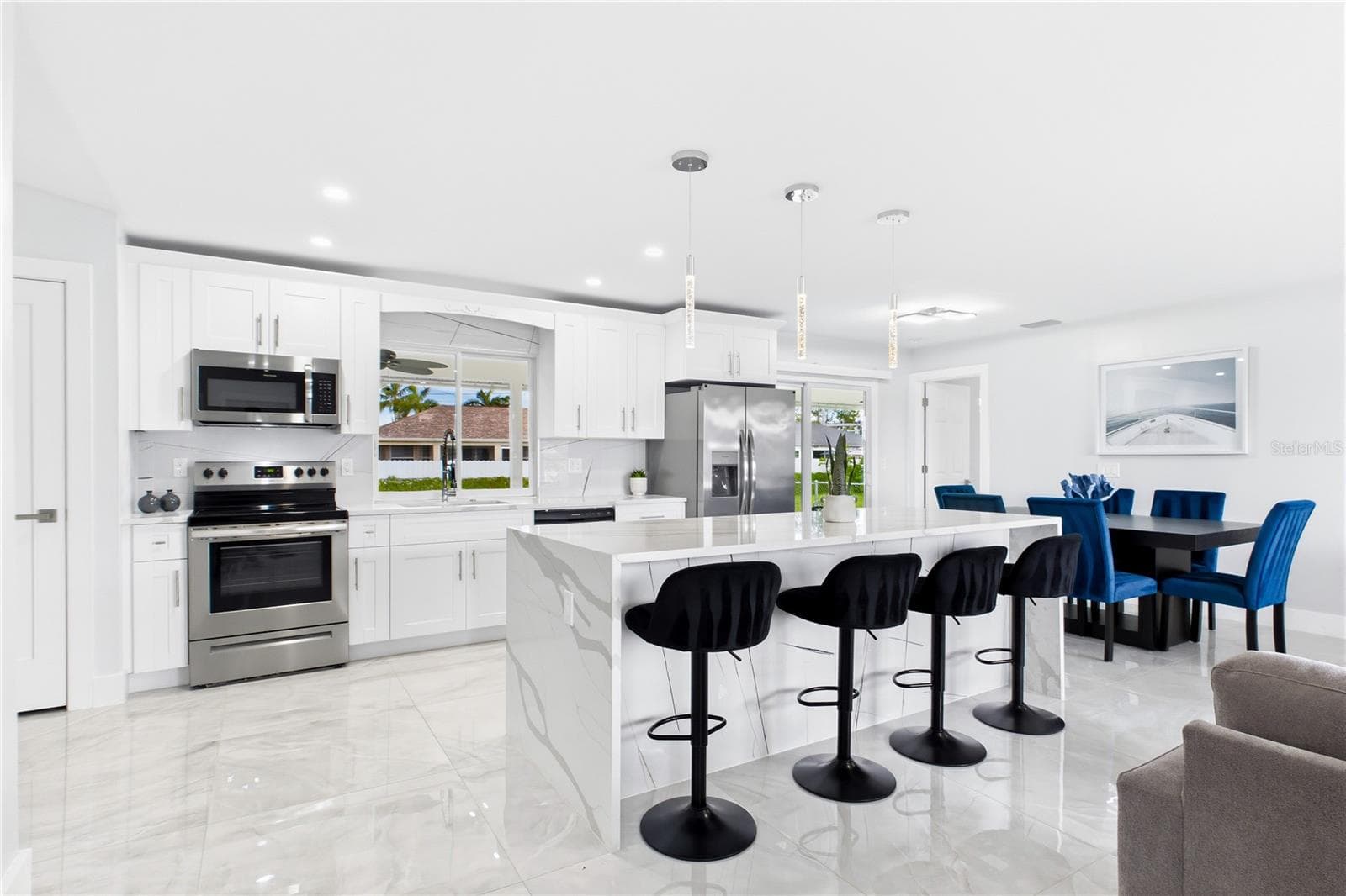 The SHOWSTOPPER KITCHEN features WHITE SHAKER CABINETRY, CALACATTA QUARTZ COUNTERTOPS, backsplash, FRIGIDAIRE STAINLESS STEEL APPLIANCES, pendant lighting - 256 SE SANTA BARBARA PL, CAPE CORAL