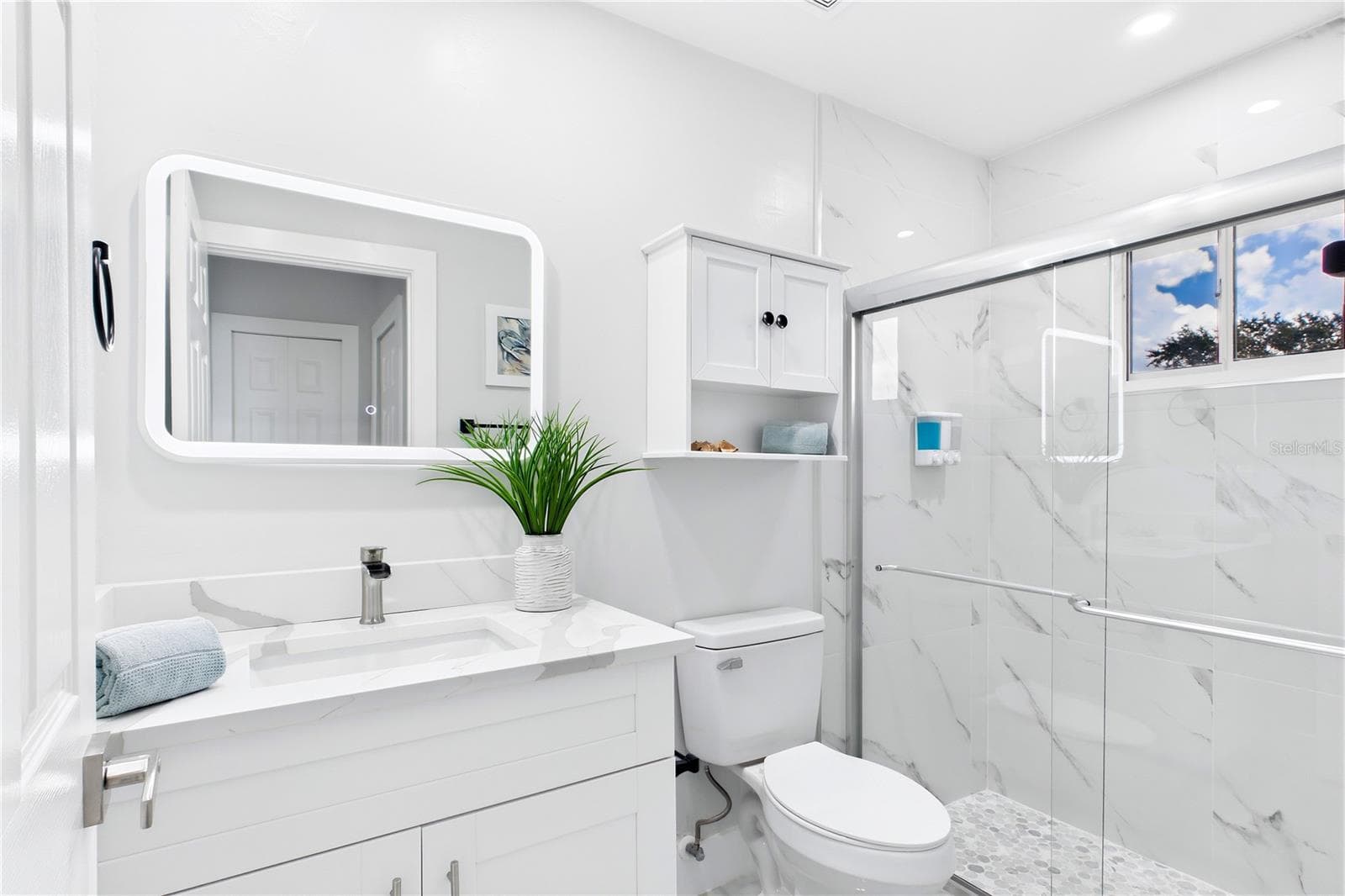 BOTH BATHROOMS were extensively renovated w/ WHITE SHAKER VANITIES, CALACATTA QUARTZ COUNTERS, illuminated mirrors, modern fixtures, LARGE-FORMAT MARBLE-LOOK SHOWER TILE & glass enclosures - 256 SE SANTA BARBARA PL, CAPE CORAL