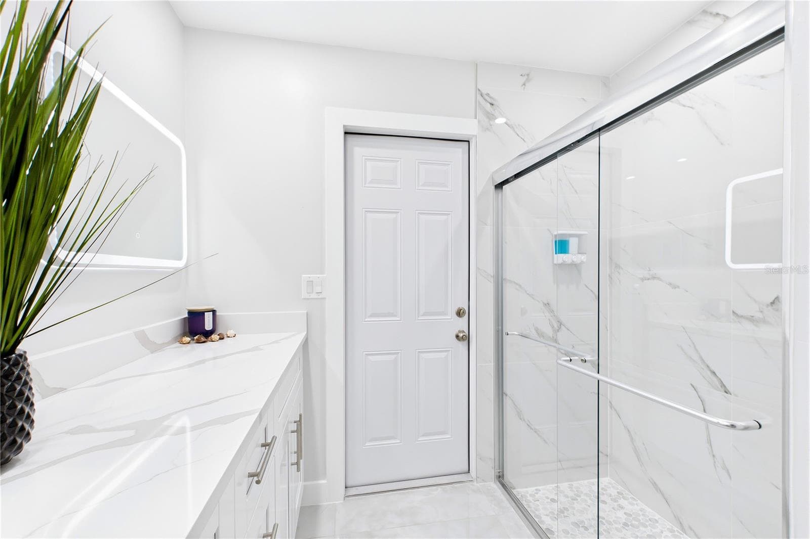 The beautifully RENOVATED SECOND BATHROOM features a WHITE SHAKER VANITY, CALACATTA QUARTZ countertop, illuminated mirror & sleek modern fixtures. - 256 SE SANTA BARBARA PL, CAPE CORAL